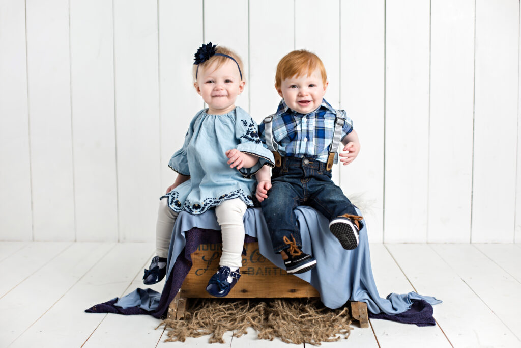 Twin boy and girl babies sitter session with matching blue outfits.