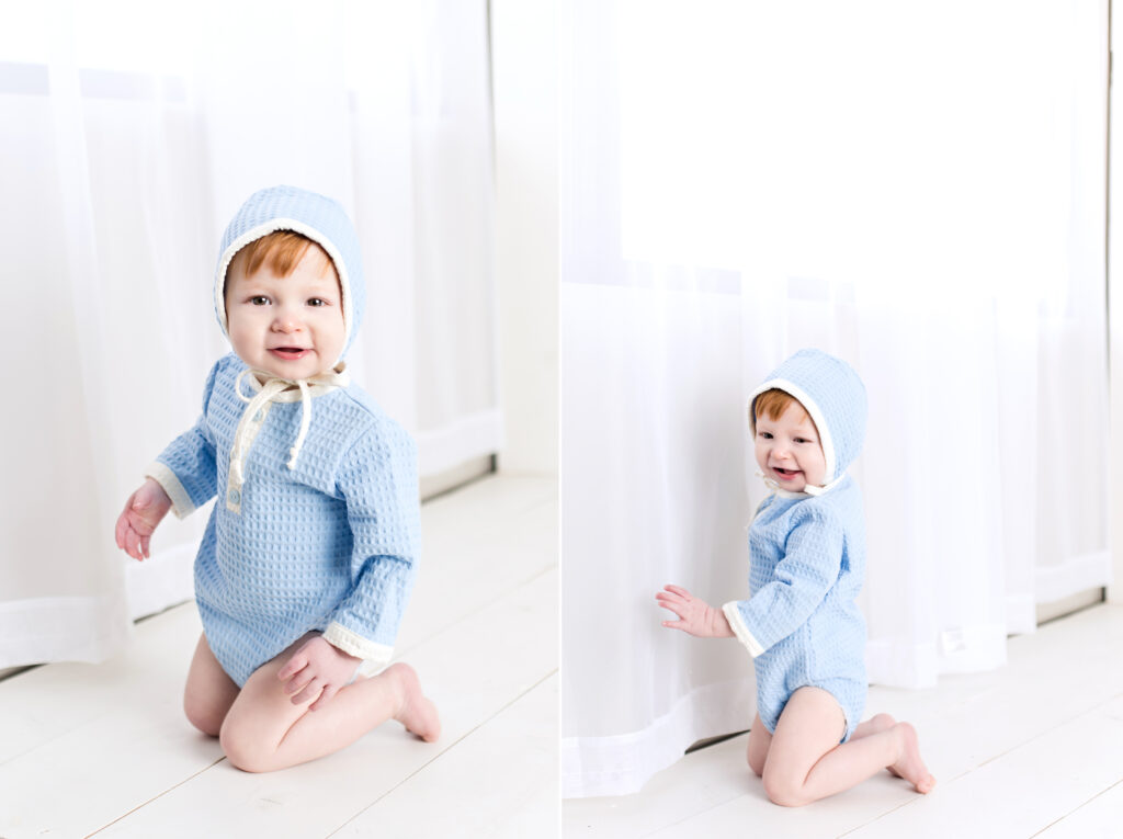 Baby boy sitter session with light blue romper and bonnet with flowing white curtain and white wood background.