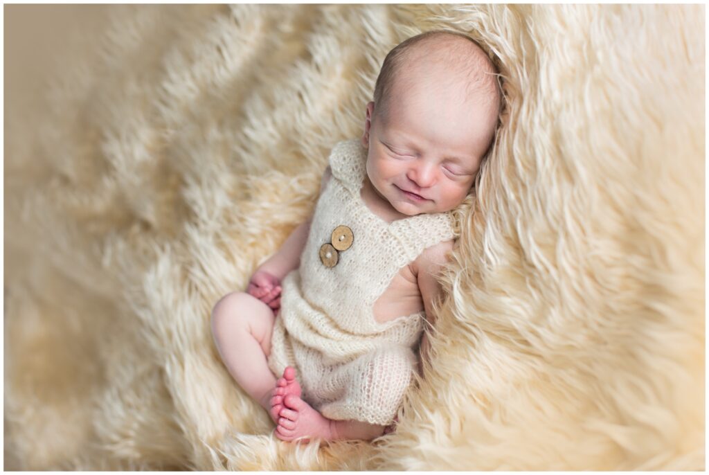 Newborn baby pose on nude flotaki wearing a nude romper | CB Studio | Iowa Photographer