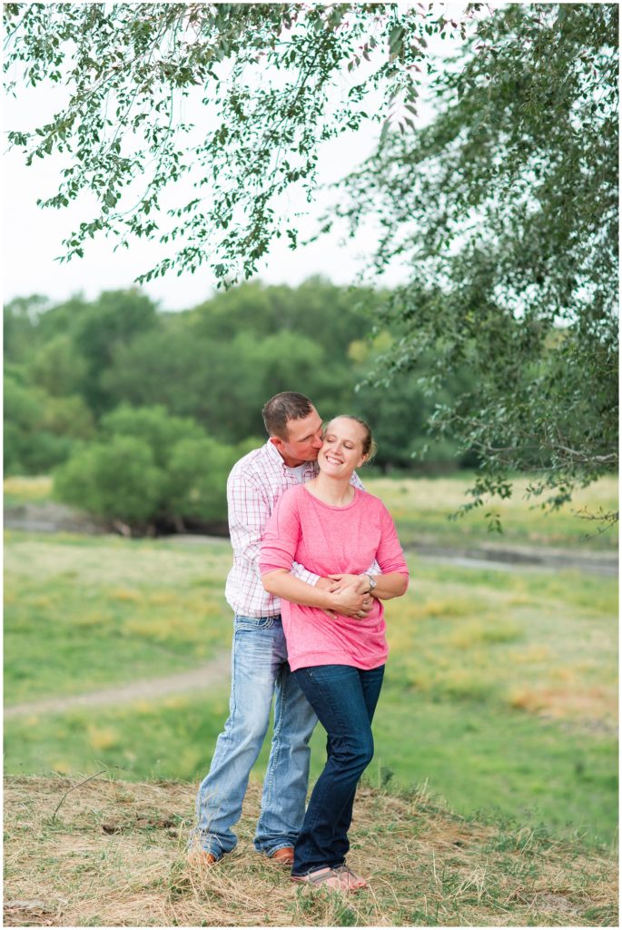 Couple poses over a scenic hill and river | Iowa Family Photographer | CB Studio