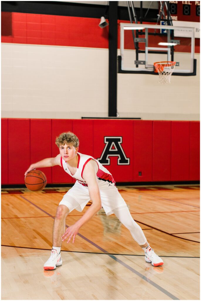Senior boy dribbling a basketball in the Algona High School gym | Iowa Senior Photographer | CB Studio
