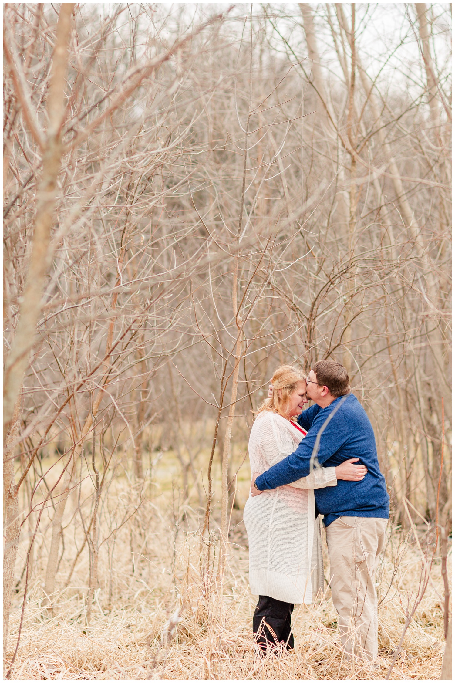 Engagement shoot in a grassy pasture in central Iowa in mid-March surrounded by trees