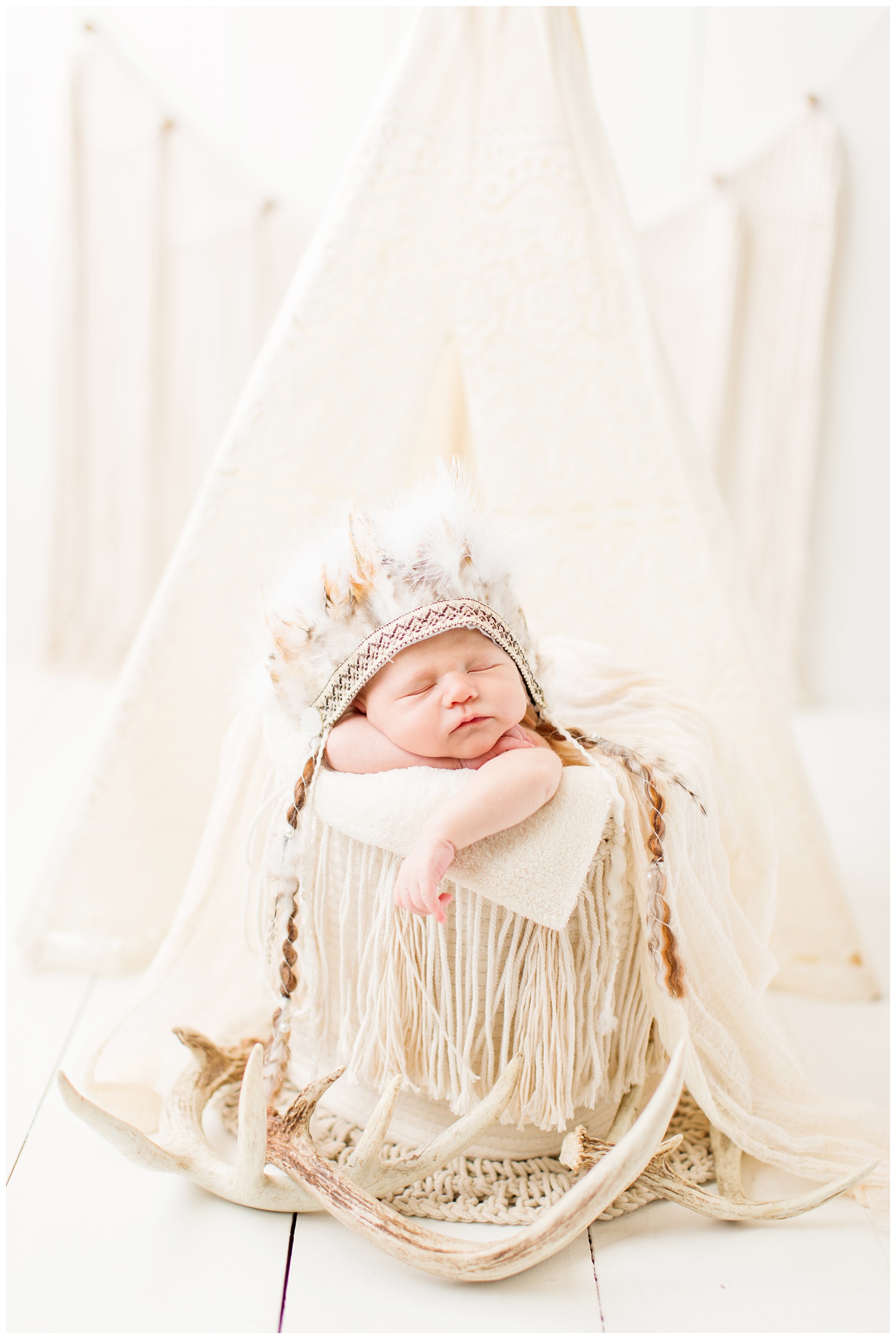 Newborn baby posing in an Indian theme photography set up wearing an Indian headdress