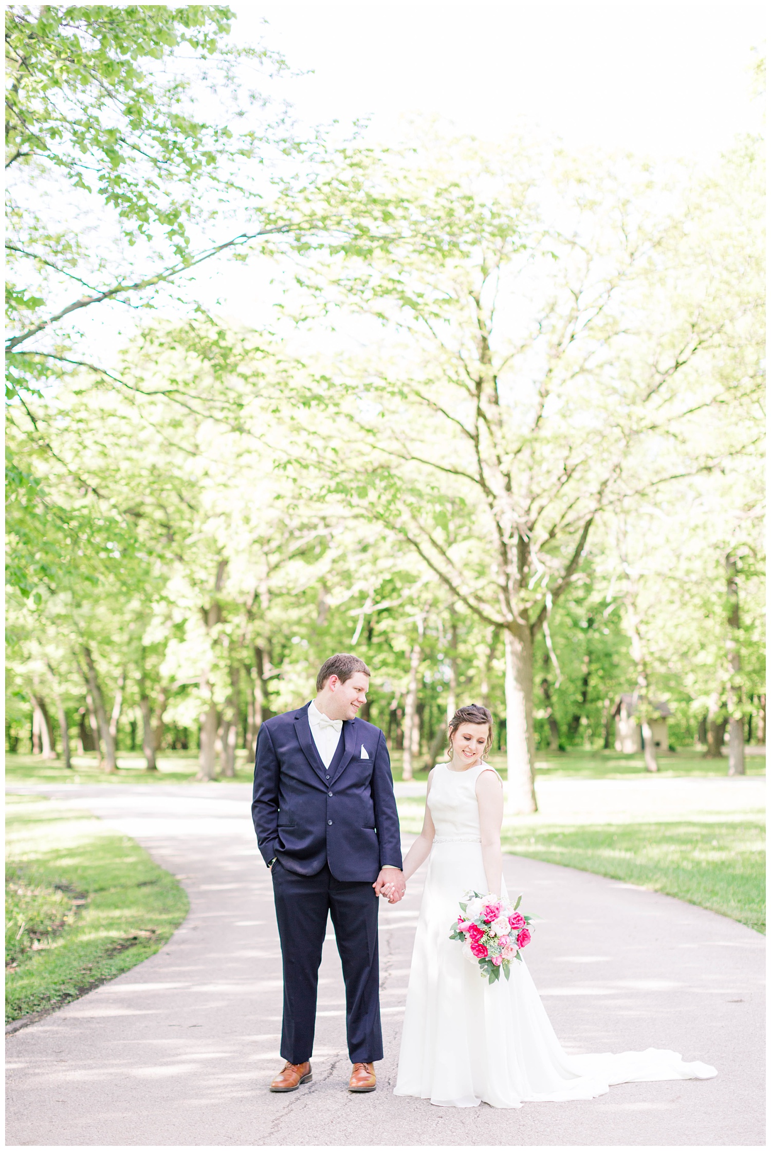 Bride and groom hold hands on a scenic path in Call Park Algona Iowa | CB Studio