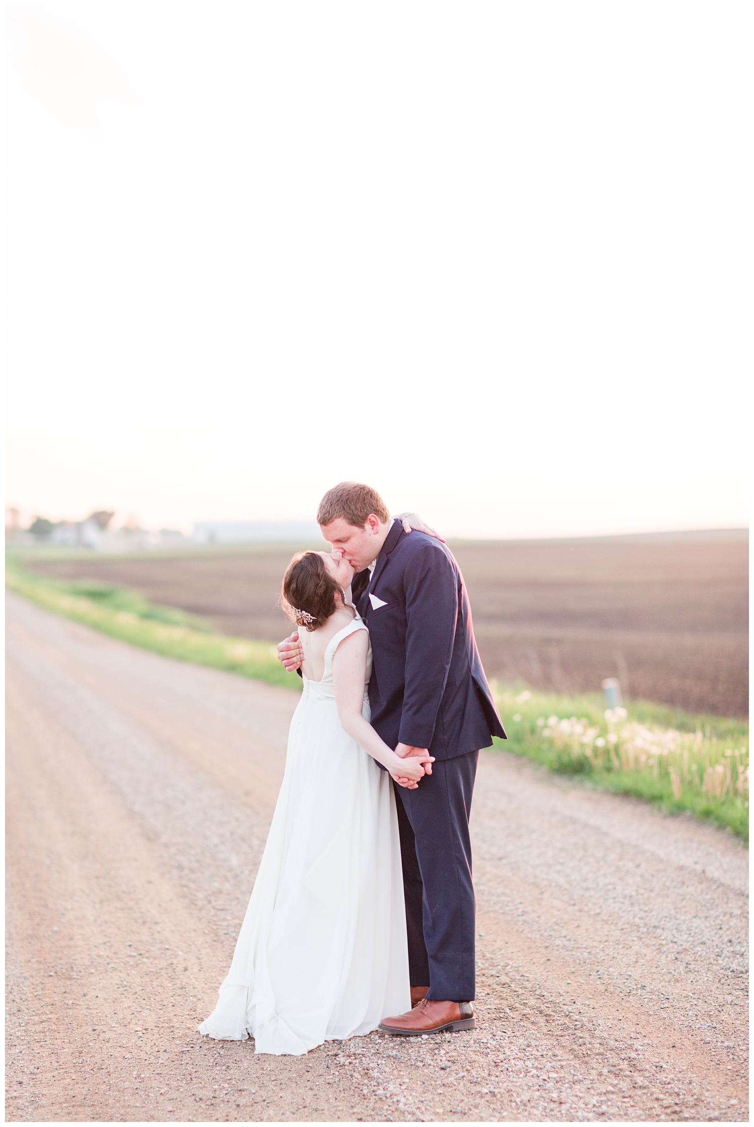 Bride and groom kiss at sunset on a country road in Algona Iowa | CB Studio