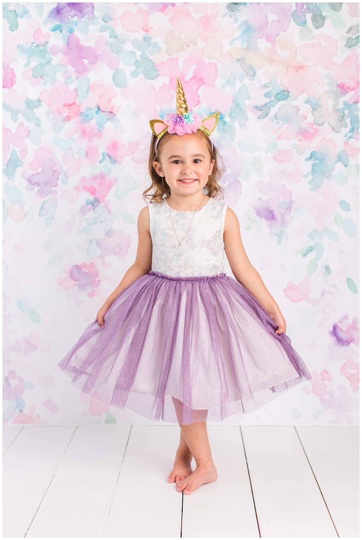 4 year old Sadie curtsey wearing a white and purple sparkling dress and unicorn headband.