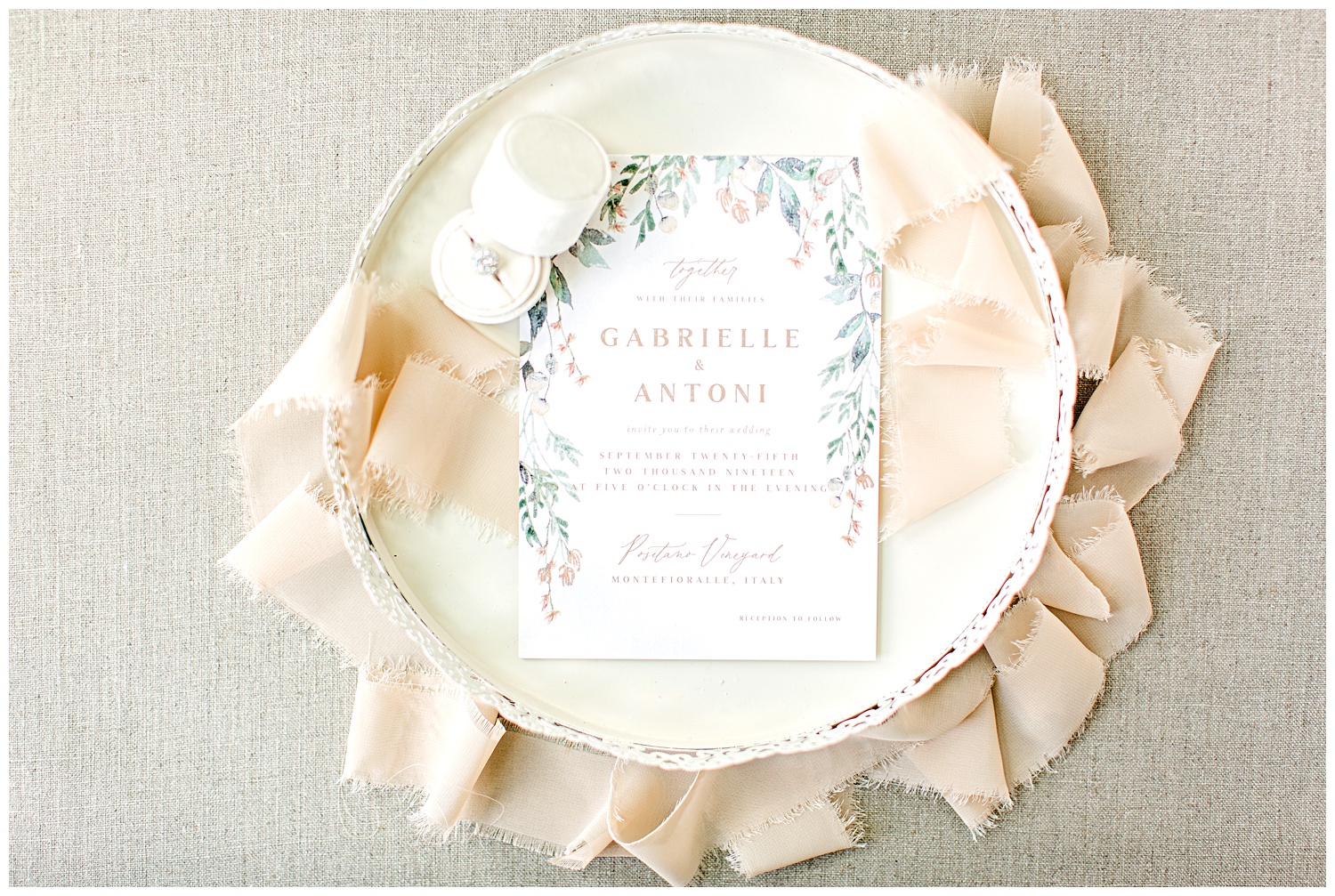 Peach, green and dusty blue watercolor floral wedding invitation from Elli beautifully styled on a cream decorative tray with a cream ring box and peach frayed edge ribbon.