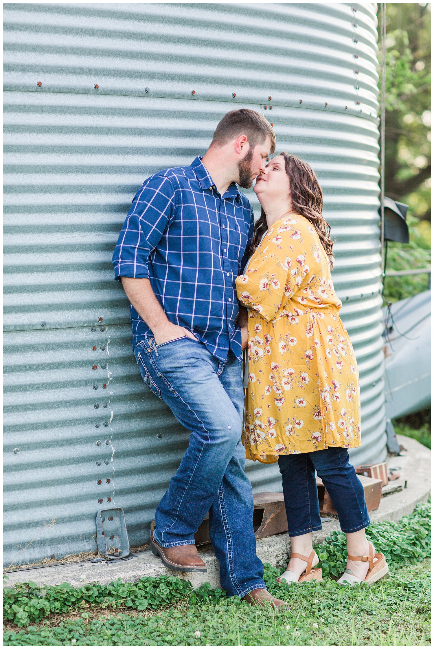 Engaged couple kiss next to a grain bin on a farm in north central Iowa | CB Studio