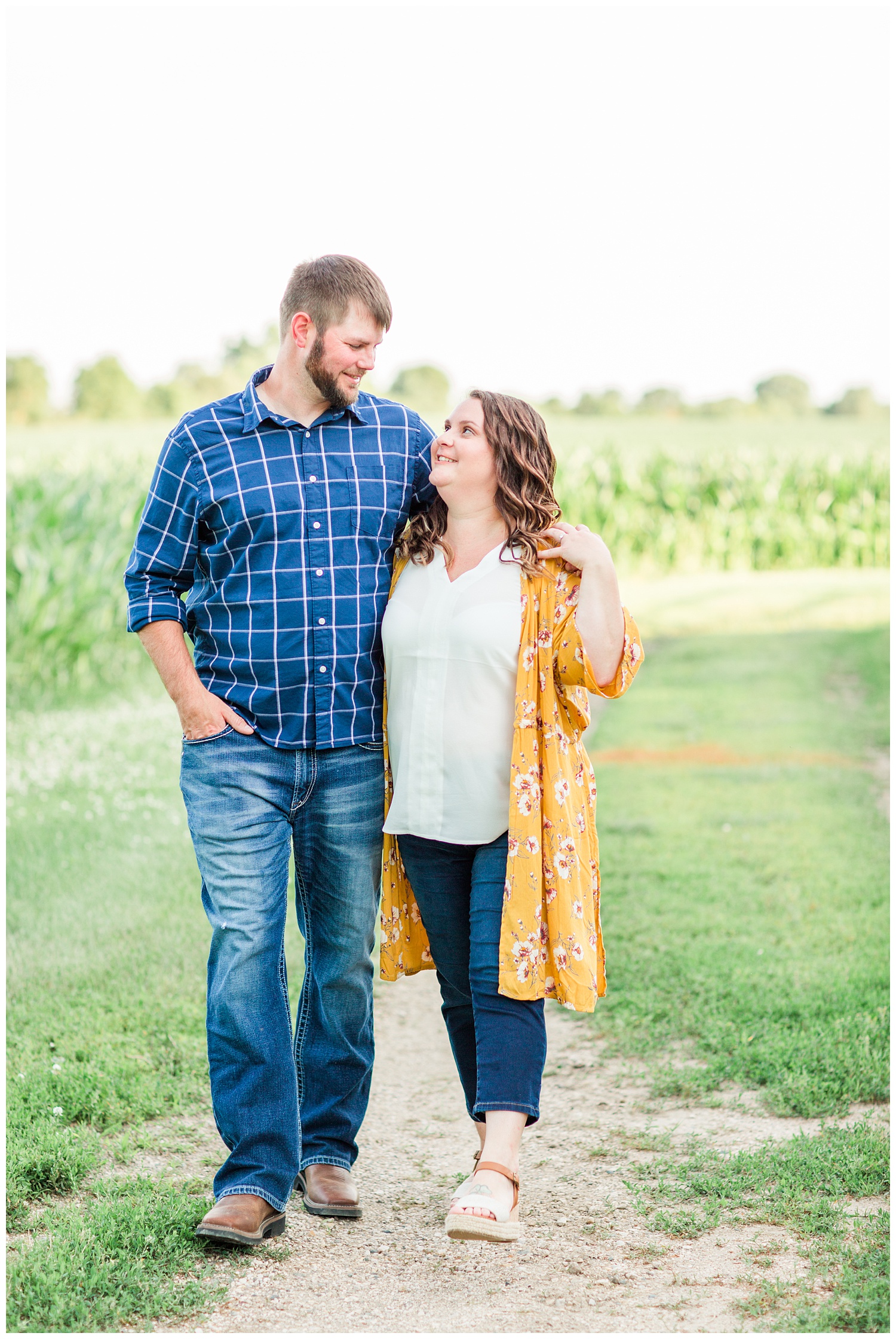 Engaged couple walks along a corn field on a farm in north central Iowa | CB Studio