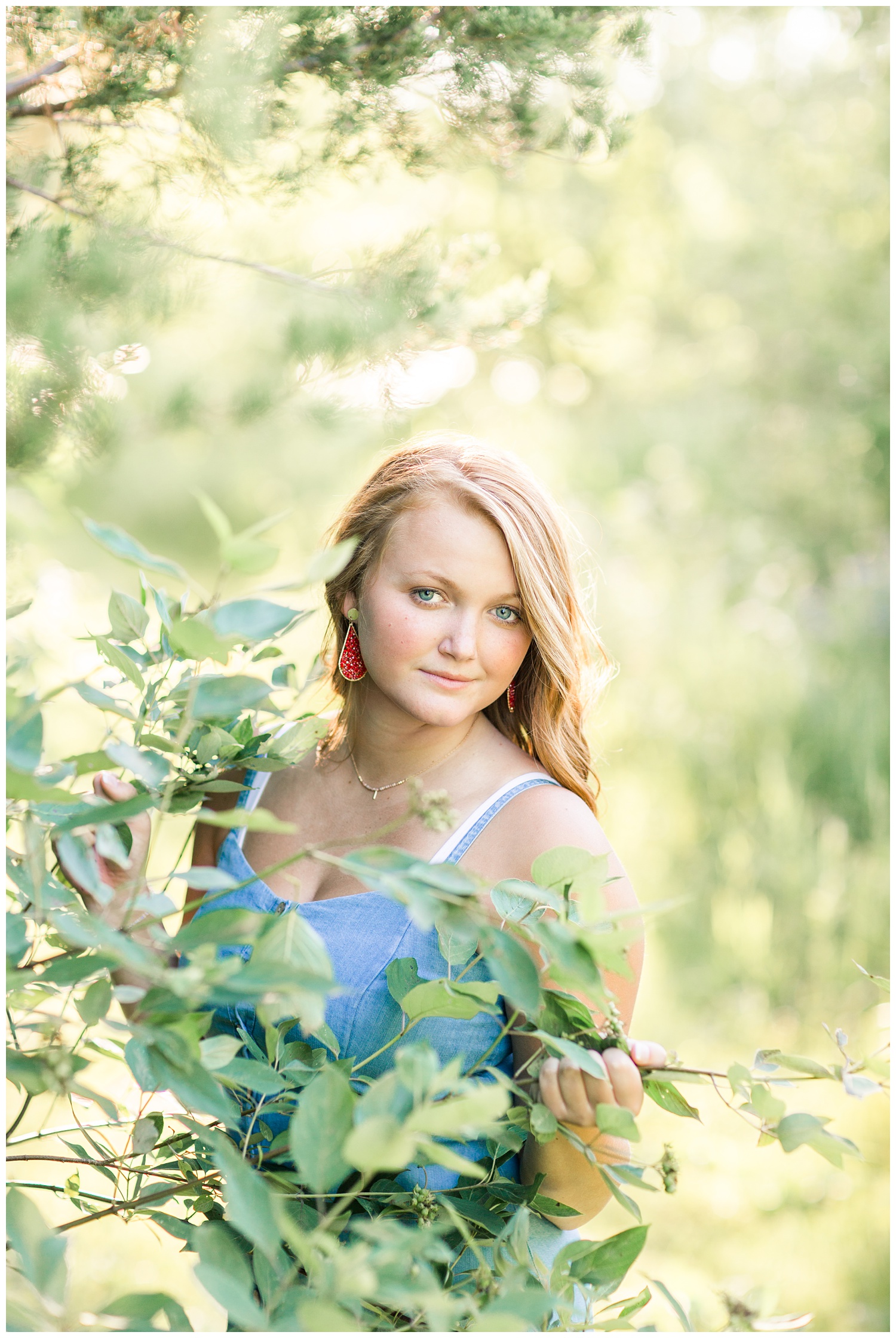 Senior girl standing behind a tree branch at Smith Lake, Algona, Iowa | CB Studio