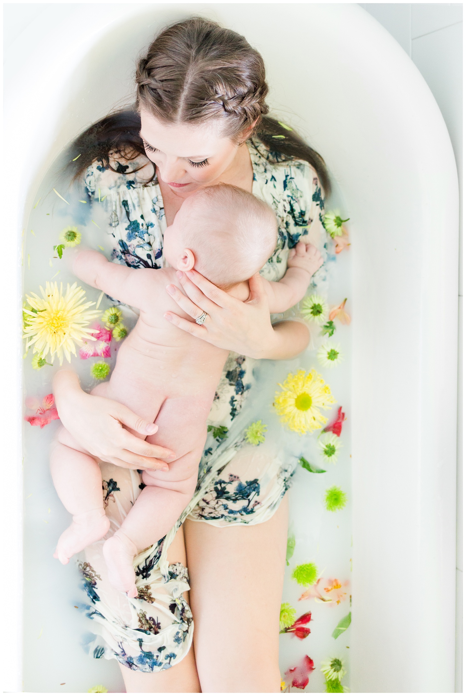 Beautiful mama lays in a white clawfoot tub in a breastfeeding milk bath surrounded by flowers snuggling her baby boy | CB Studio