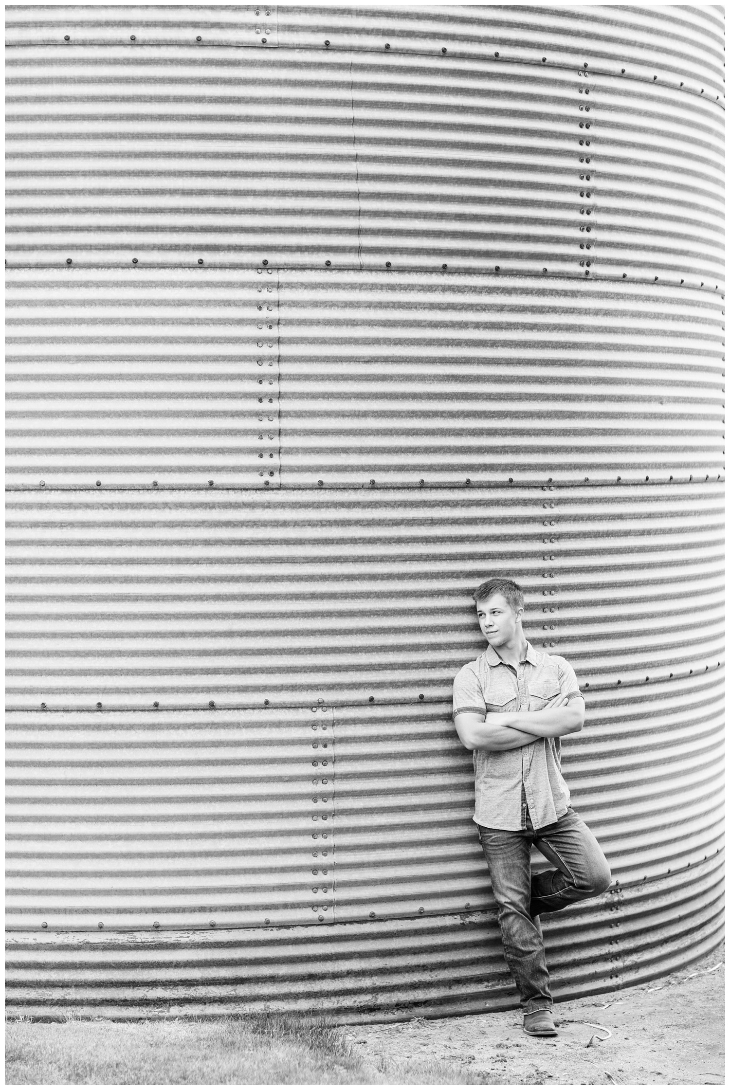 Senior boy leans against a grain bin a on rural Iowa farm | CB Studio
