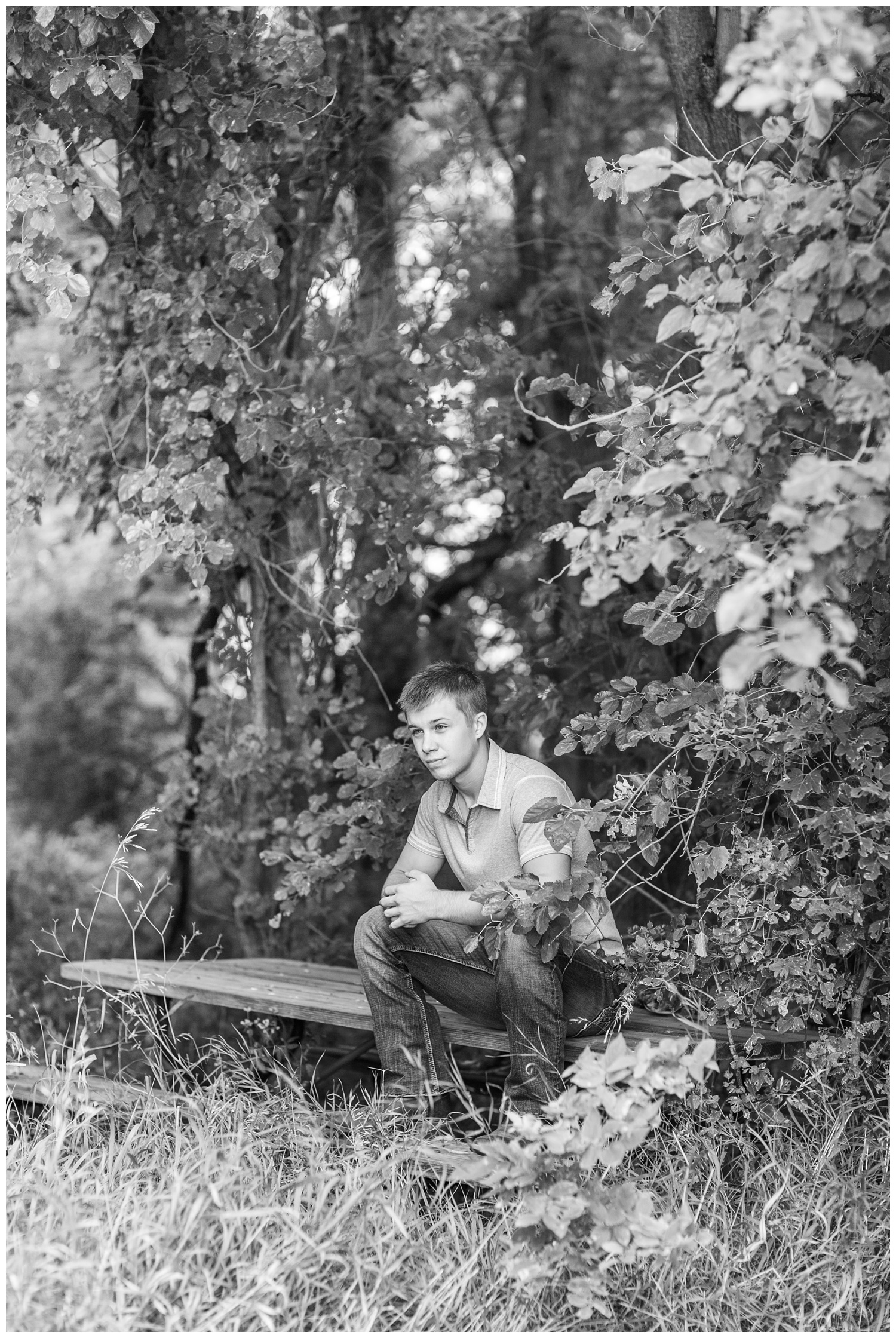 Senior boy sits on an old picnic bench tuck inside the woods a on rural Iowa farm | CB Studio