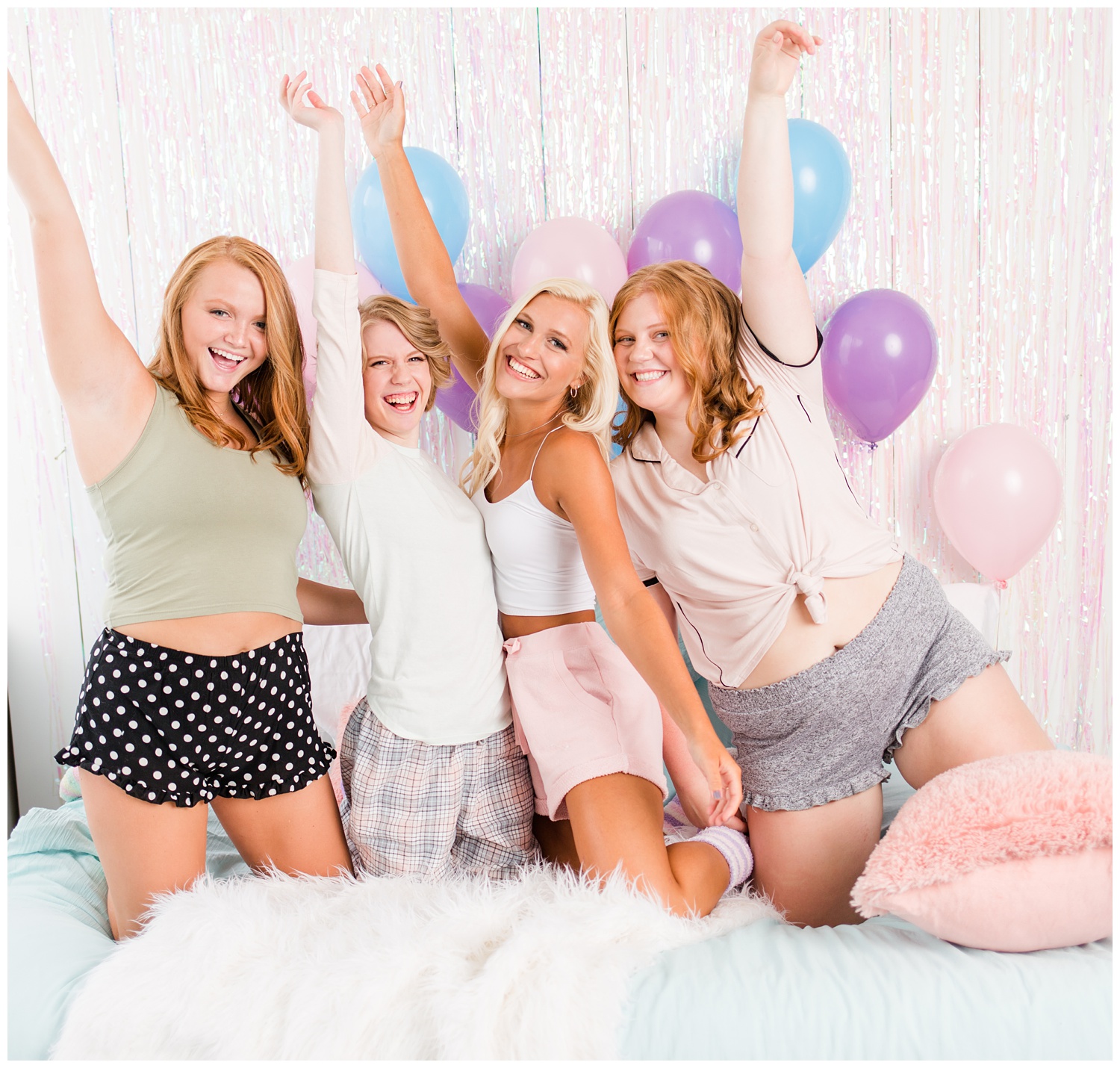 Senior girls laughing during a senior sleepover-styled photoshoot with iridescent streamers and balloons. | CB Studio