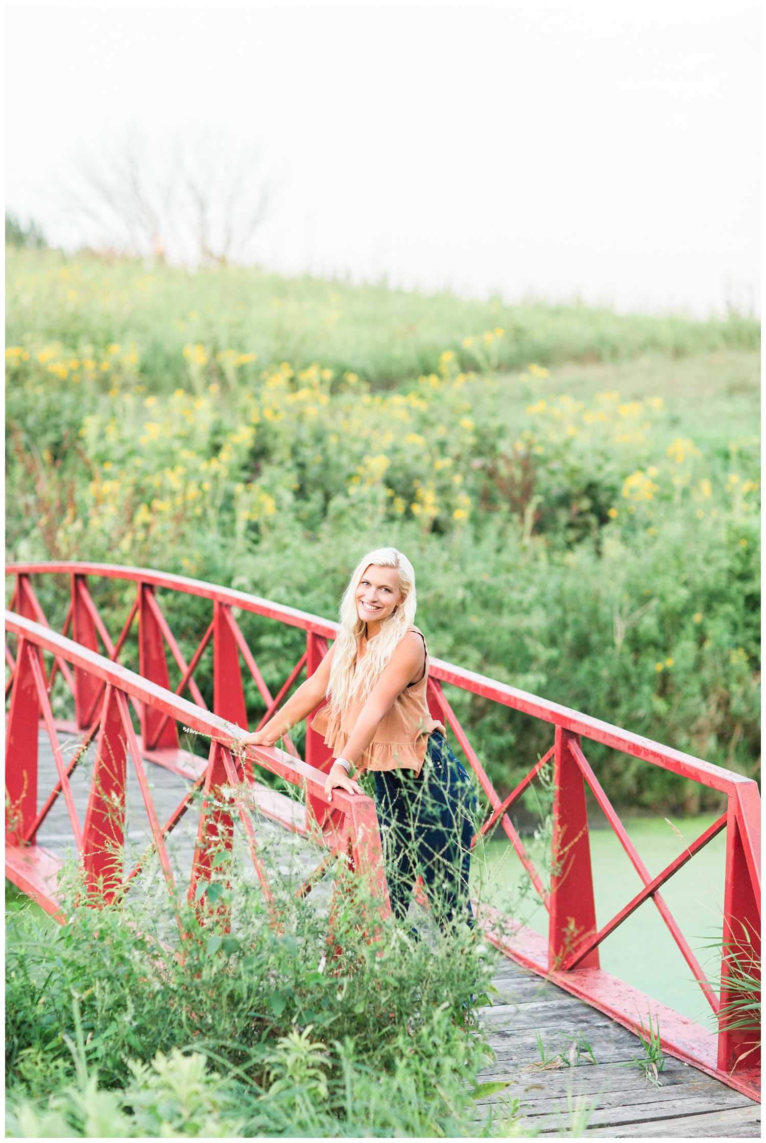 Senior girl standing on a red bridge at Water's Edge Nature Center in Algona, Iowa | CB Studio