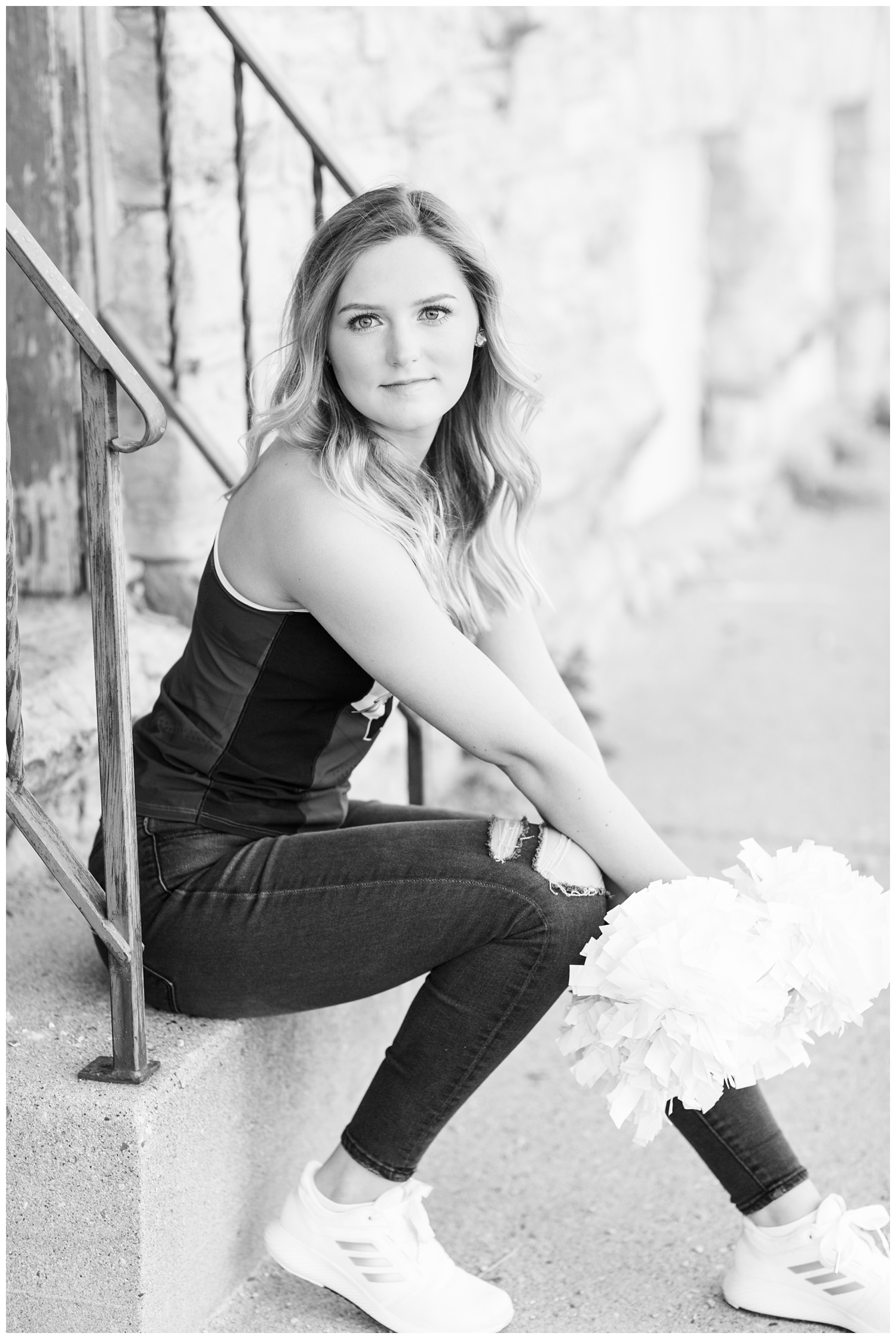 Senior dance photography girl holding dance poms sitting on a step in downtown Humboldt, Iowa | CB Studio
