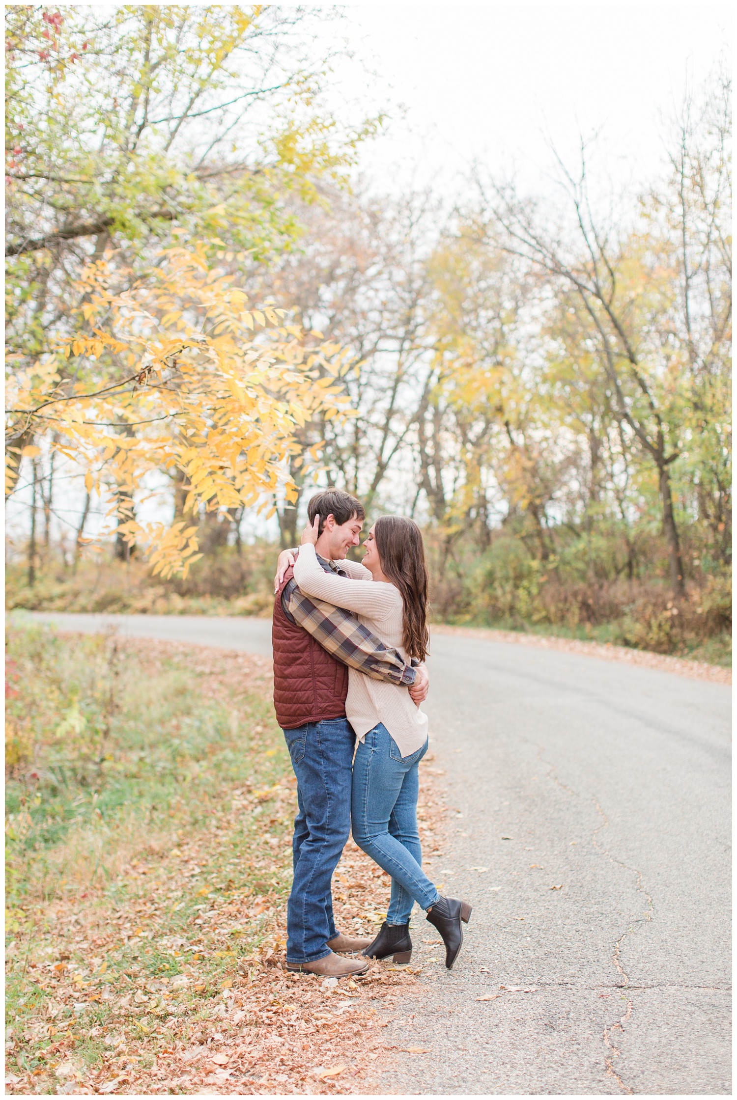 Fall in Iowa, Jenna embraces Brady in the middle of an autumn path at Lost Island Nature Center | CB Studio