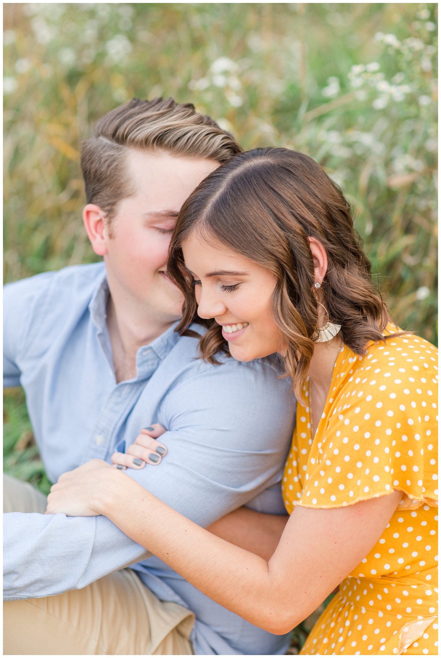 Jadi and Luke snuggle close in a grassy field in Iowa during the fall for engagement photos | CB Studio