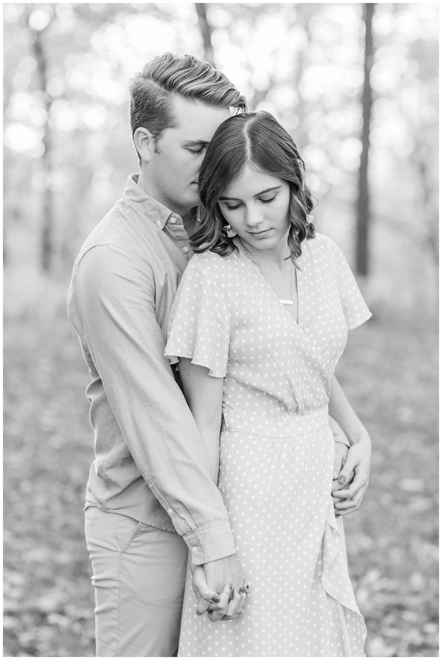 Jadi wearing a yellow flowing dress lovingly looks down as Luke whispers into her ear while embracing together in a grassy field in Iowa during the fall for engagement photos | CB Studio