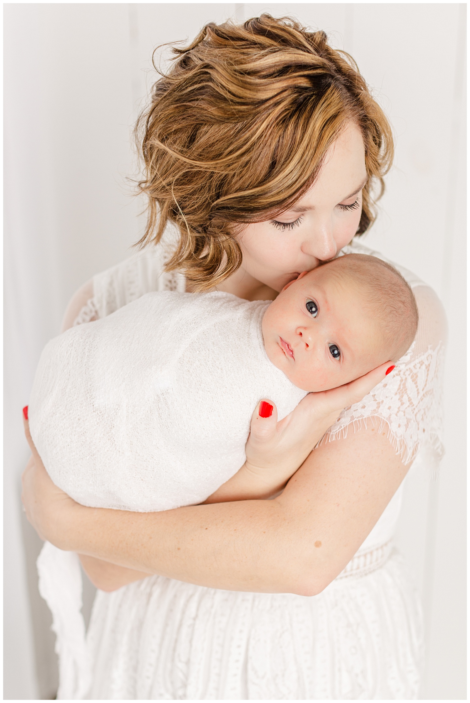 Bree dressed in white lace snuggles and gently kisses her new baby boy | CB Studio