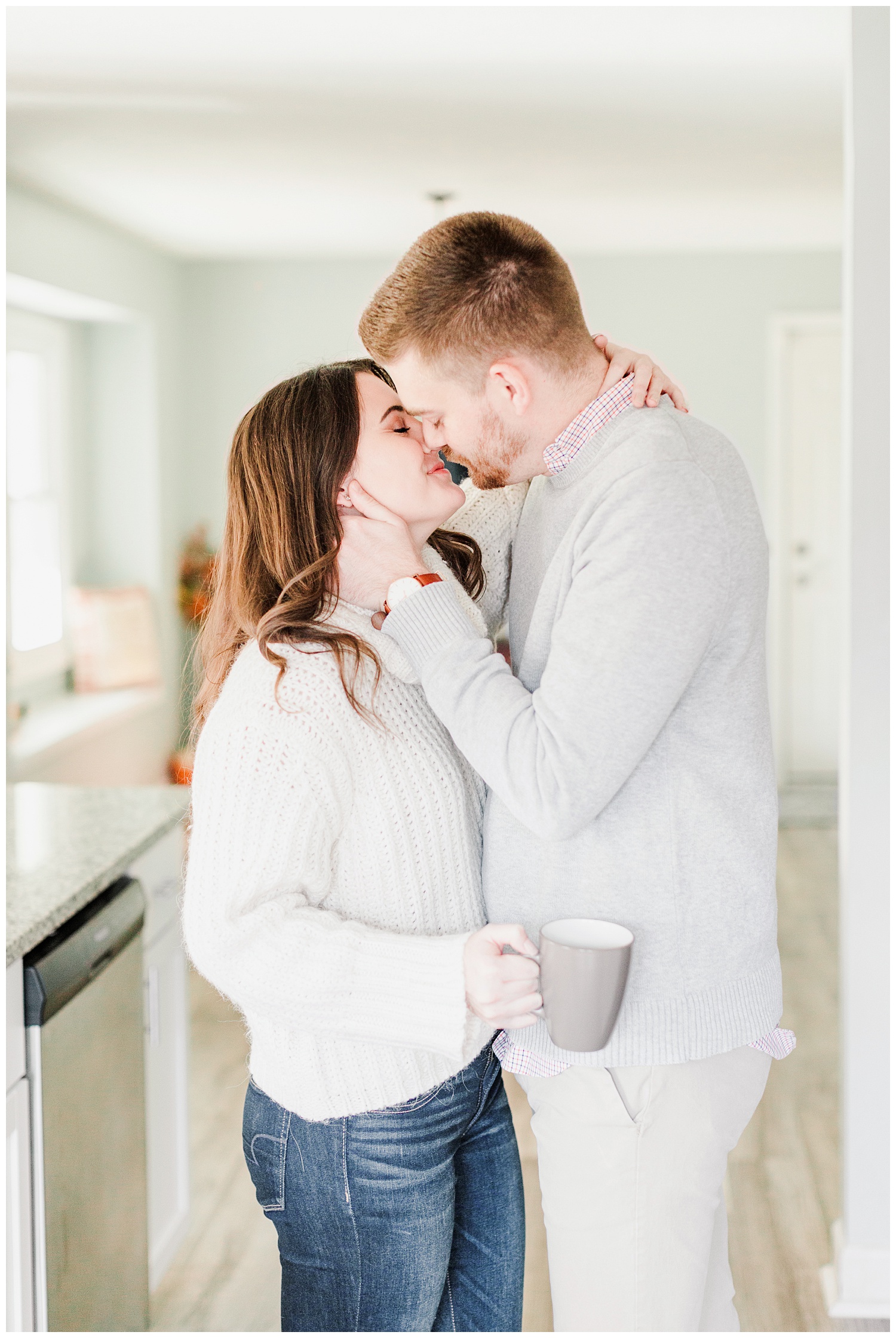 Dustin kisses Jenna while holding a cup of coffee | Cozy Kitchen Engagement Session | CB Studio