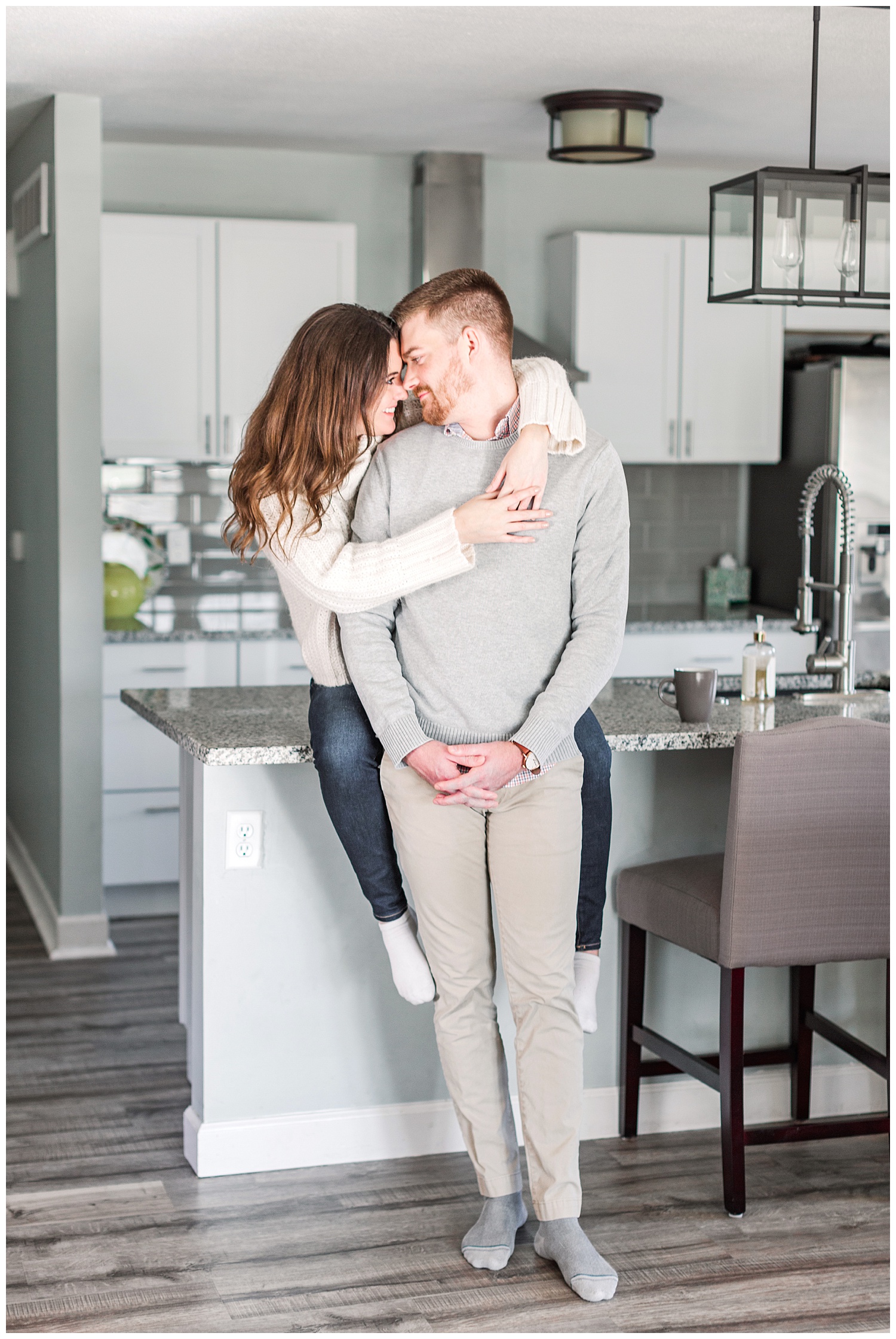 Jenna embraces Dustin while nuzzling together on their kitchen counter | Cozy Kitchen Engagement Session | CB Studio