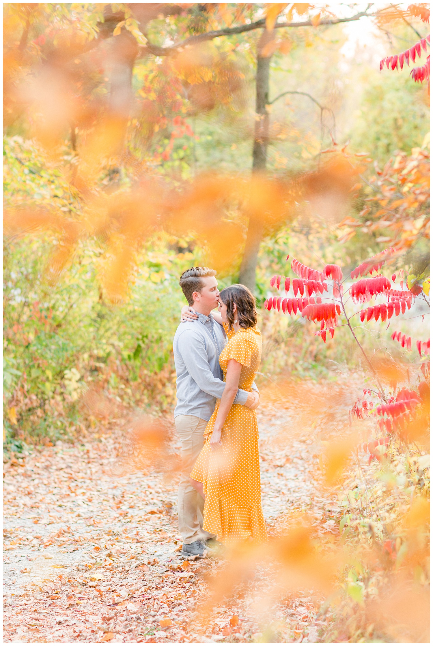 Luke kisses his girl on the forehead as they embrace in the middle of a fall wooded driveway | Iowa Wedding Photographer