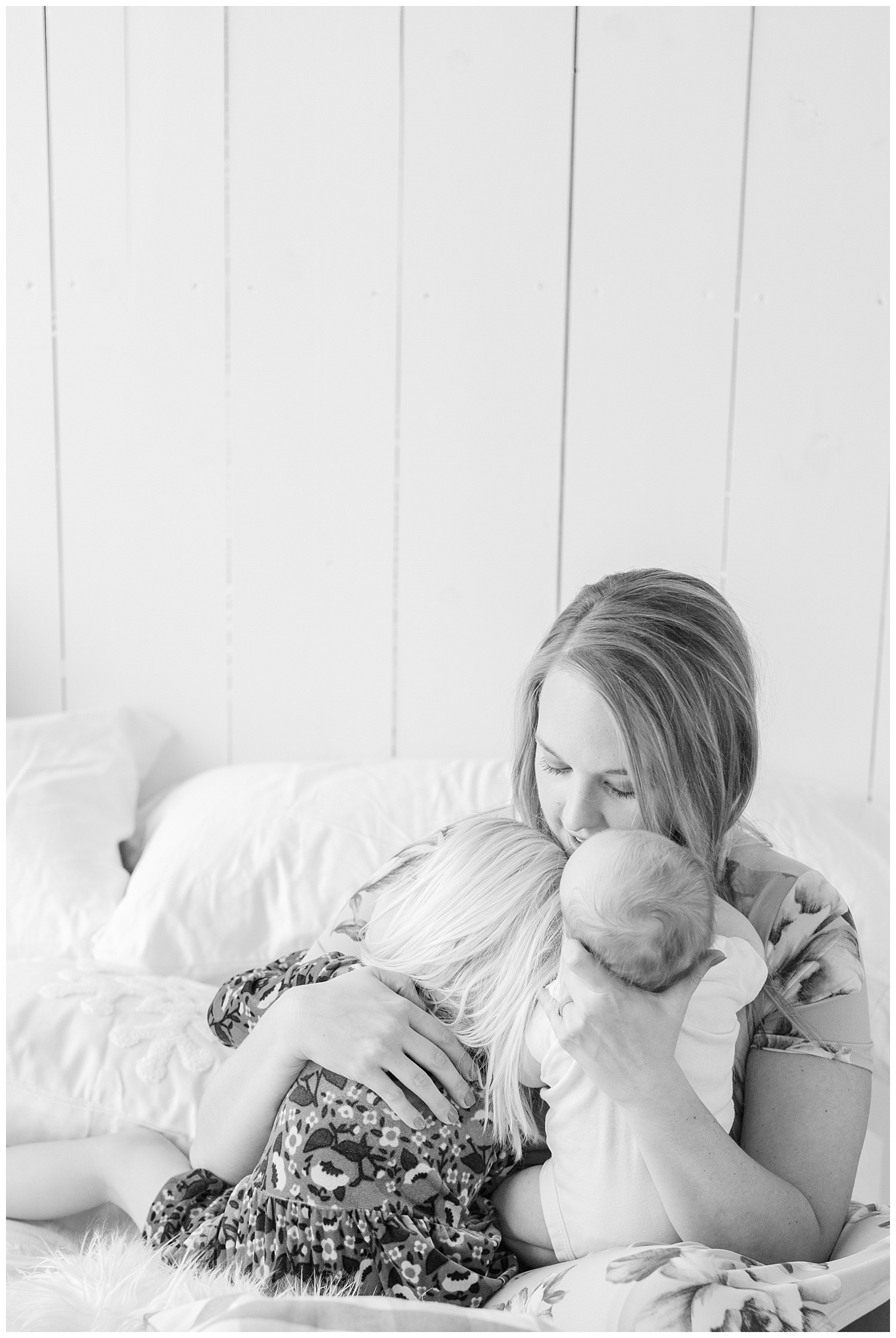 A mama snuggling her two babies during a snuggle photography session, her three year old toddler and newborn baby boy. | CB Studio