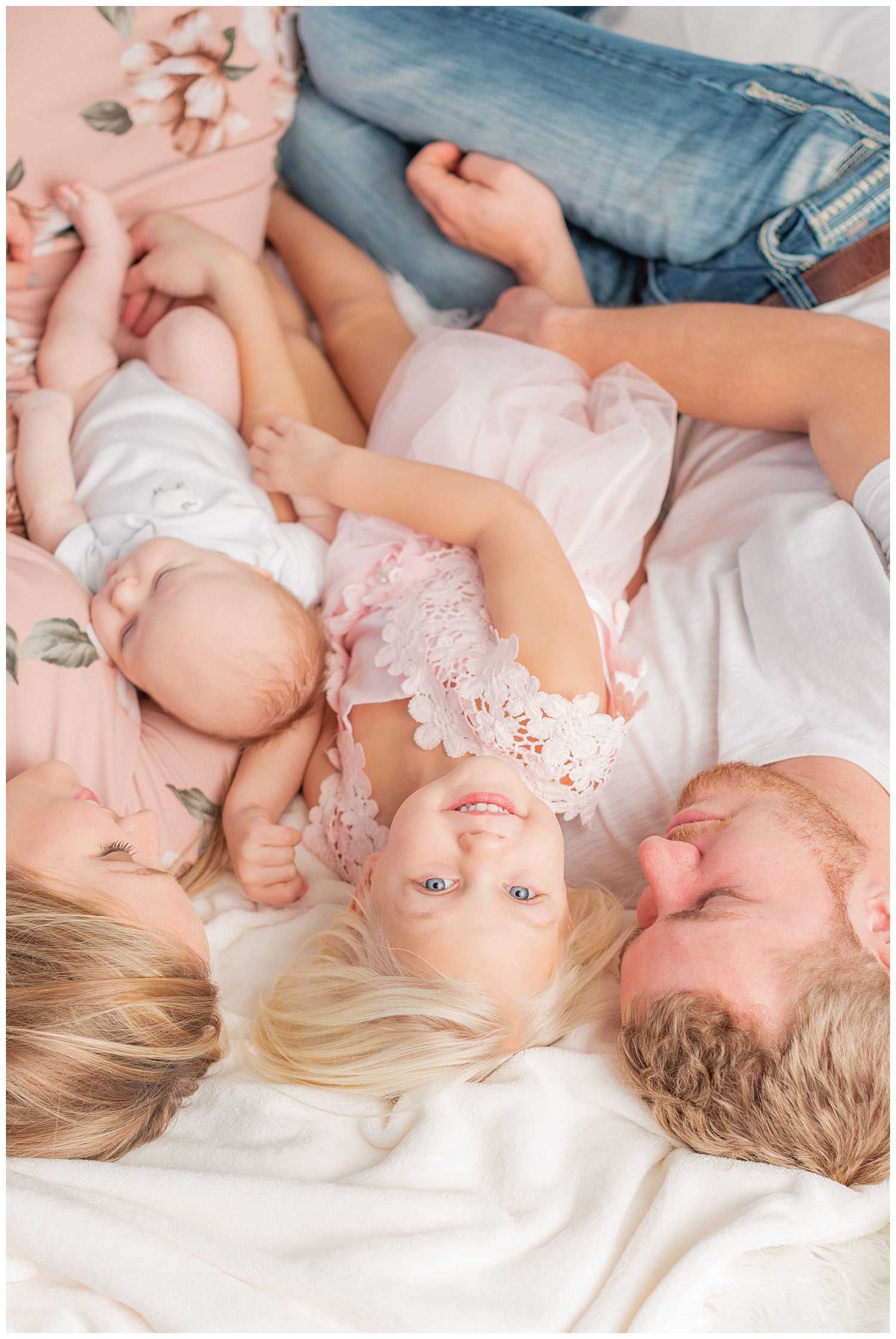 A young family snuggle together while three year old Stella looks up during a snuggle photography session | CB Studio