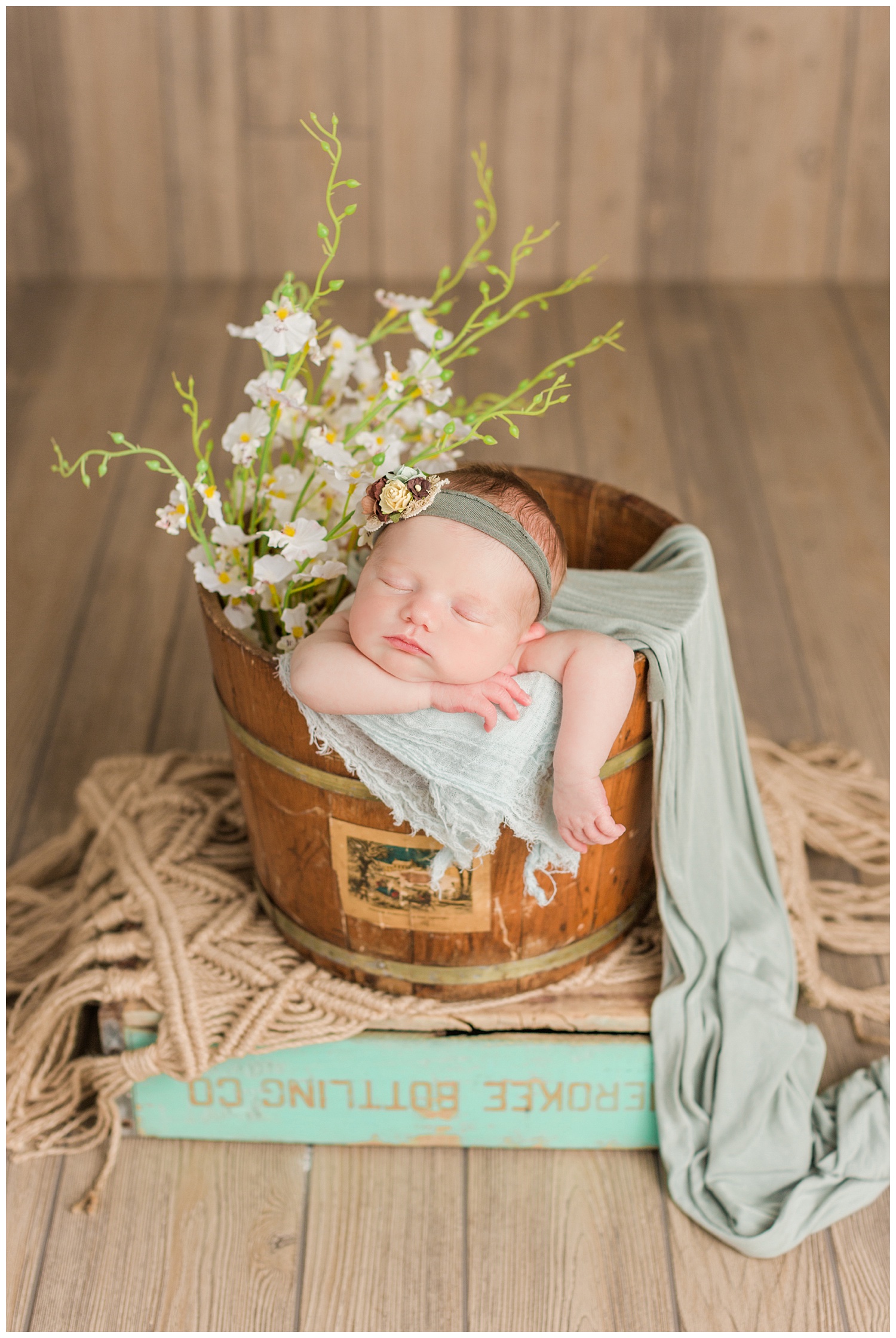 Baby Scarlett posed in a rustic bucket and box with white florals and pops of sage and mint | CB Studio