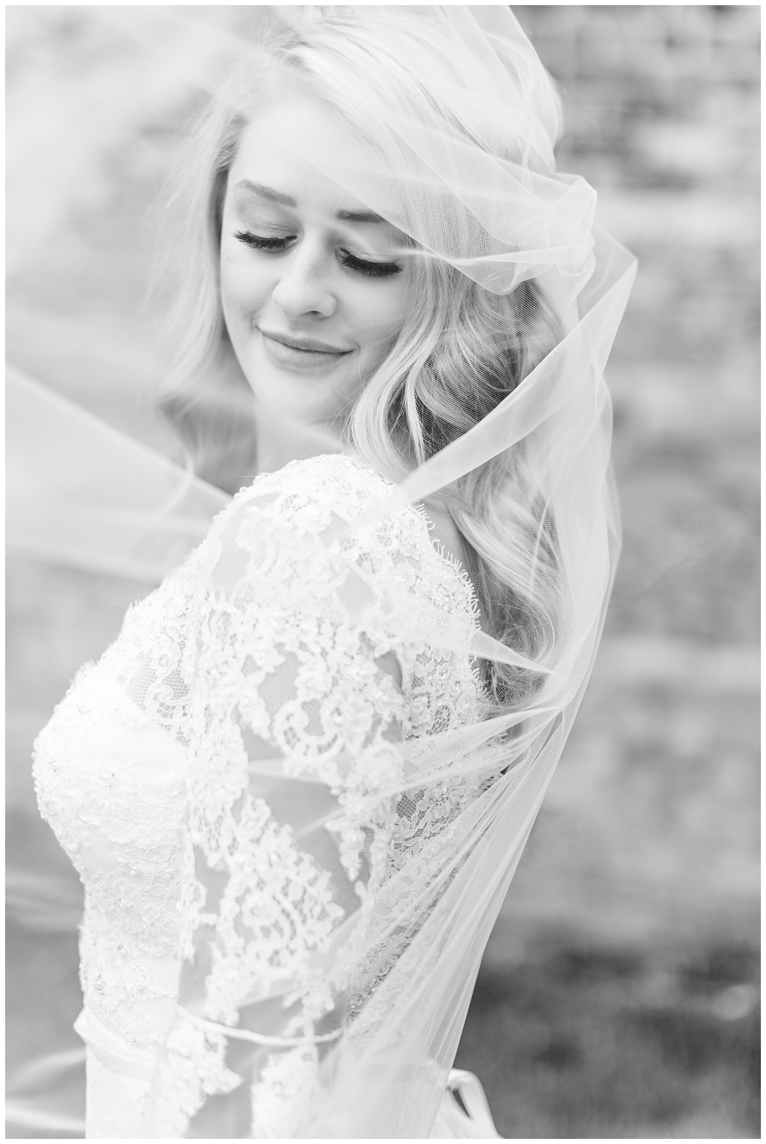 Beautiful bride looks down as her veil blows in the wind | CB Studio
