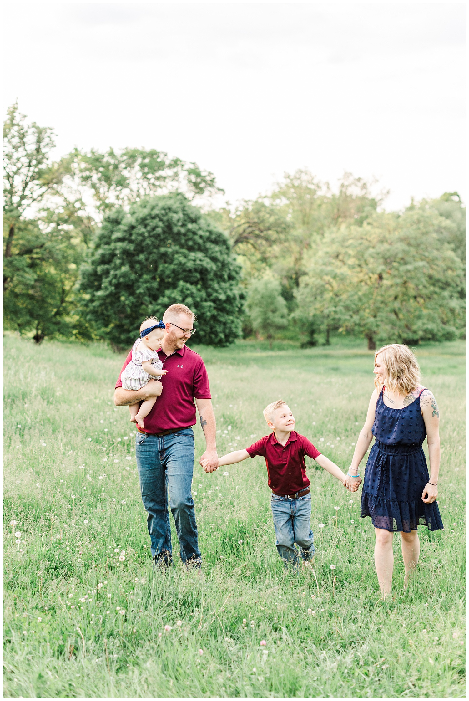 Family walks hand in hand in a grassy pasture with rolling hills in Iowa | CB Studio
