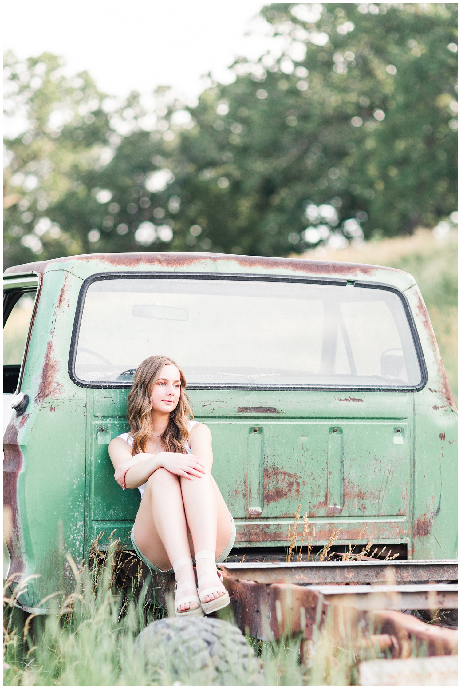 Senior Taylor sitting in the back of an old green Ford truck in a grassy field | CB Studio
