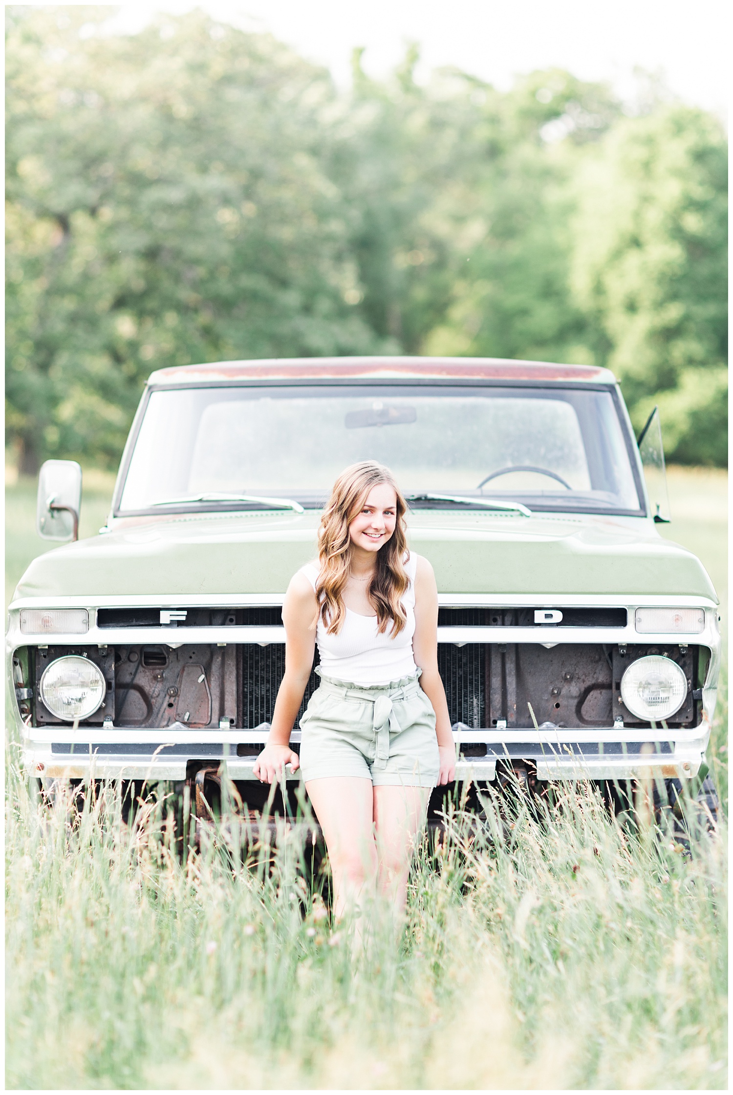 Senior Taylor leaning against an old green Ford truck in a grassy field | CB Studio