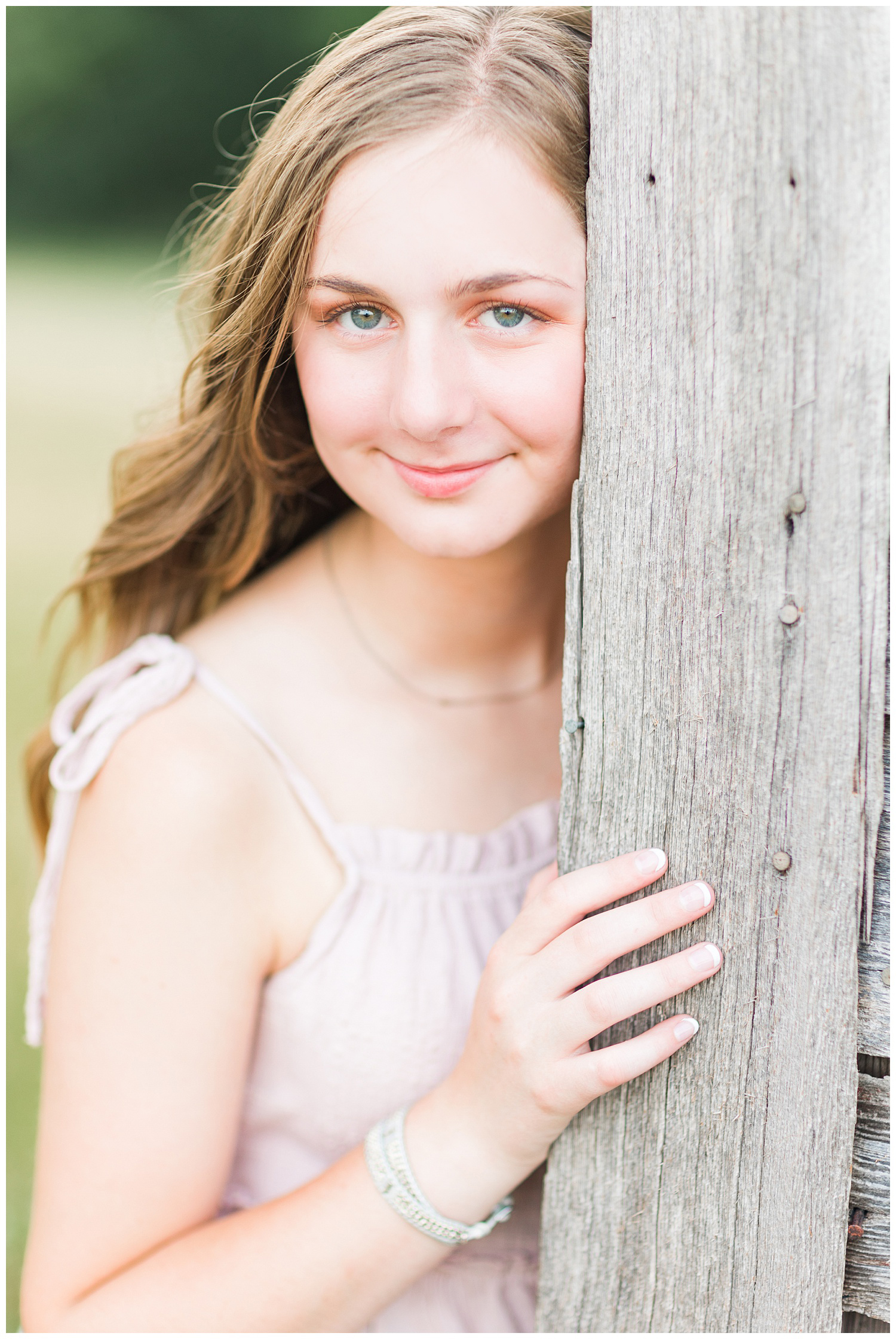 Senior Taylor smiles softly as she leans against an old wood barn | CB Studio
