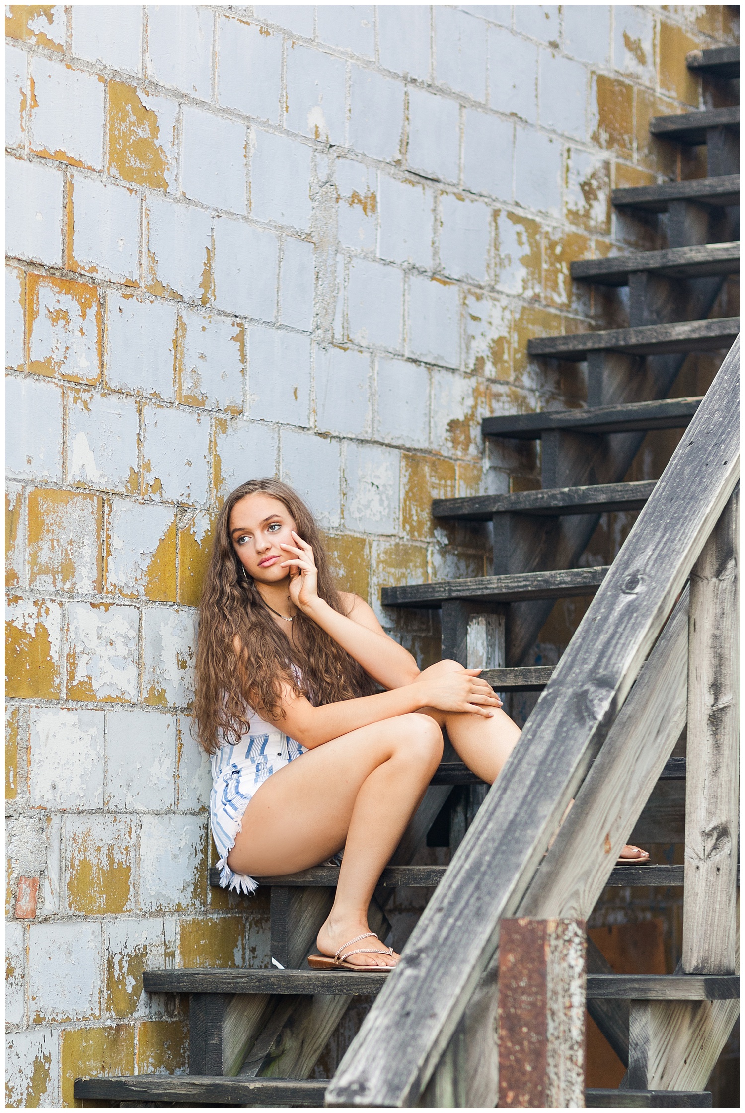 Senior Kennedy sits on an old wooden staircase in downtown Fort Dodge | CB Studio