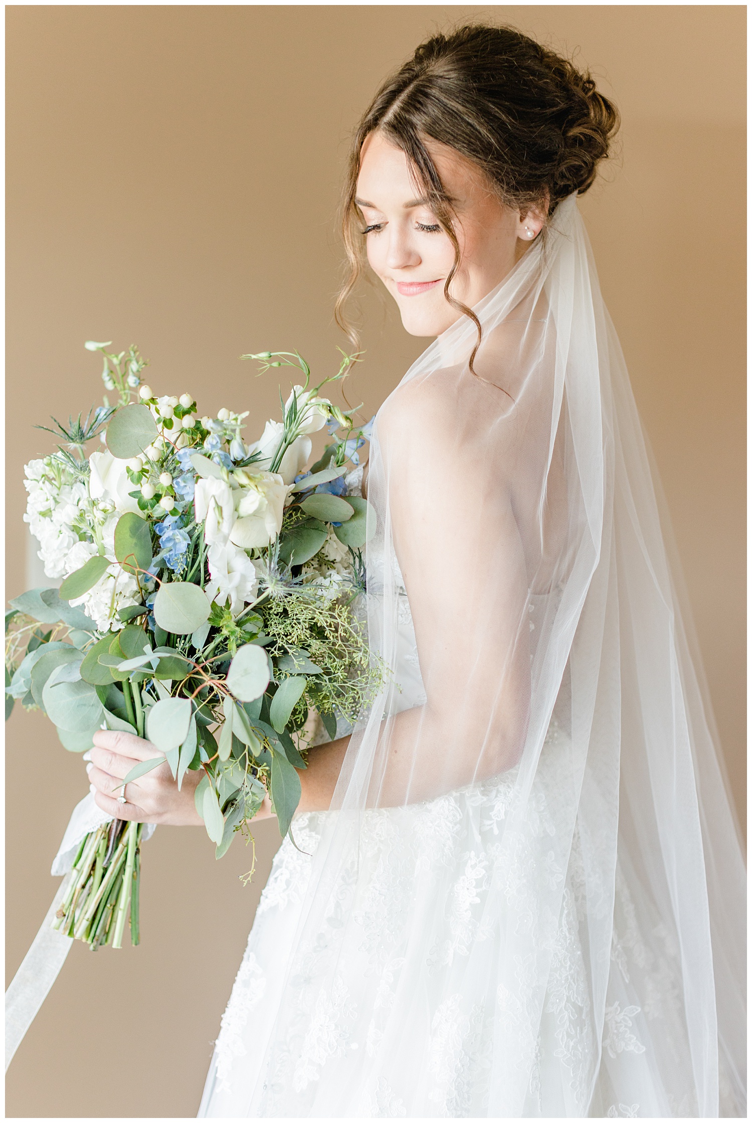 Bride Jenna wearing Sophia Tolli and holding her loose gathered bouquet of white roses, sea holly, and eucalyptus | CB Studio