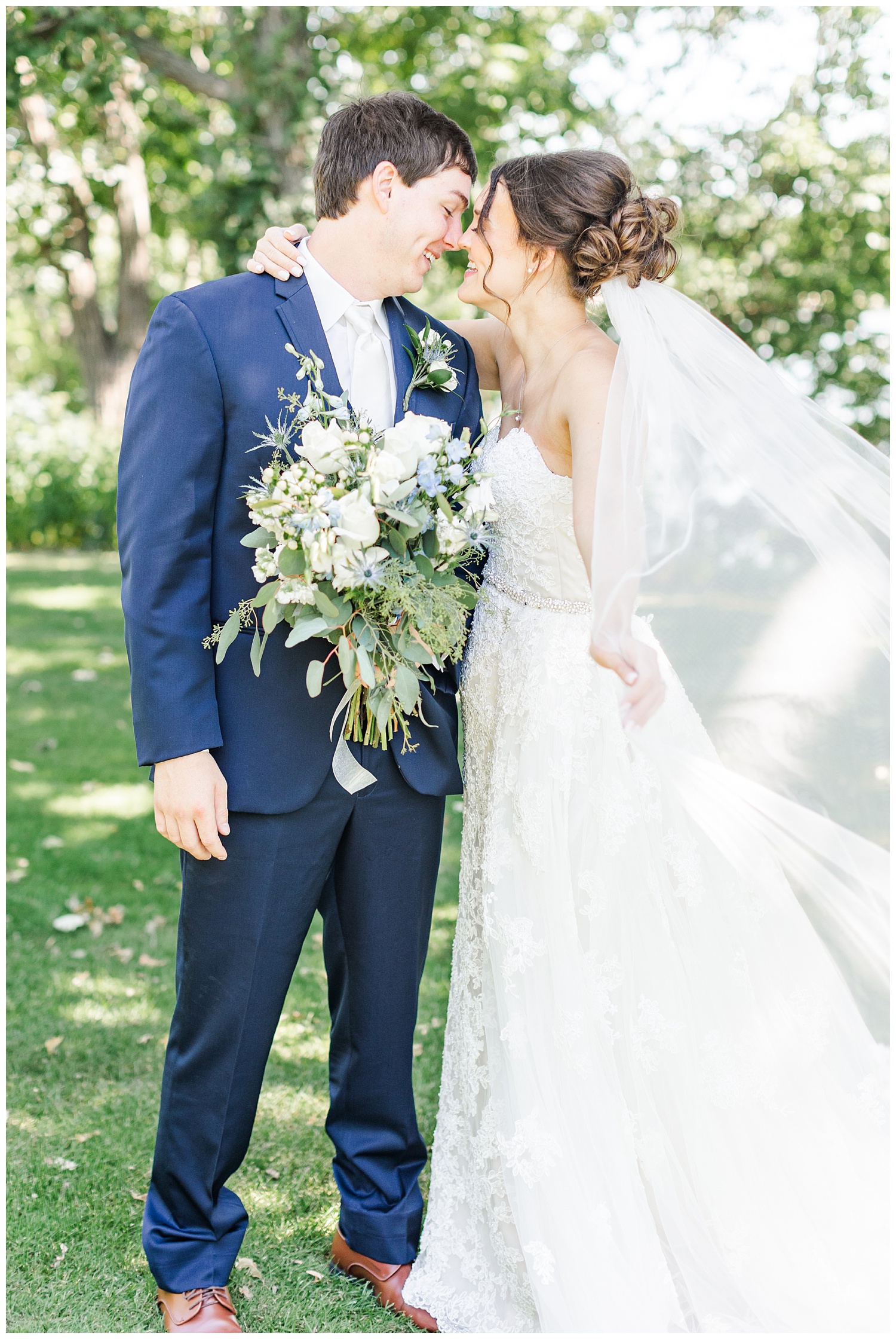 Bride and groom embrace and laugh while her veil blows in the wind | CB Studio