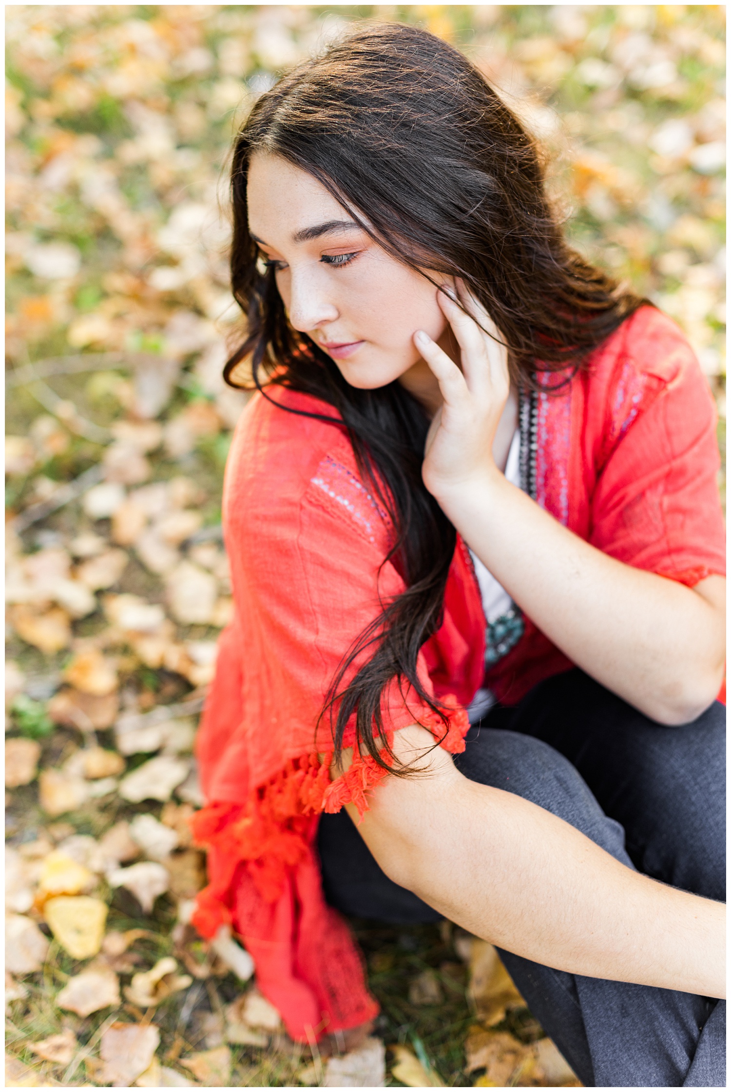 Laney, wearing a coral Kimono, looks over her shoulder while sitting on a bed of fall leaves | CB Studio