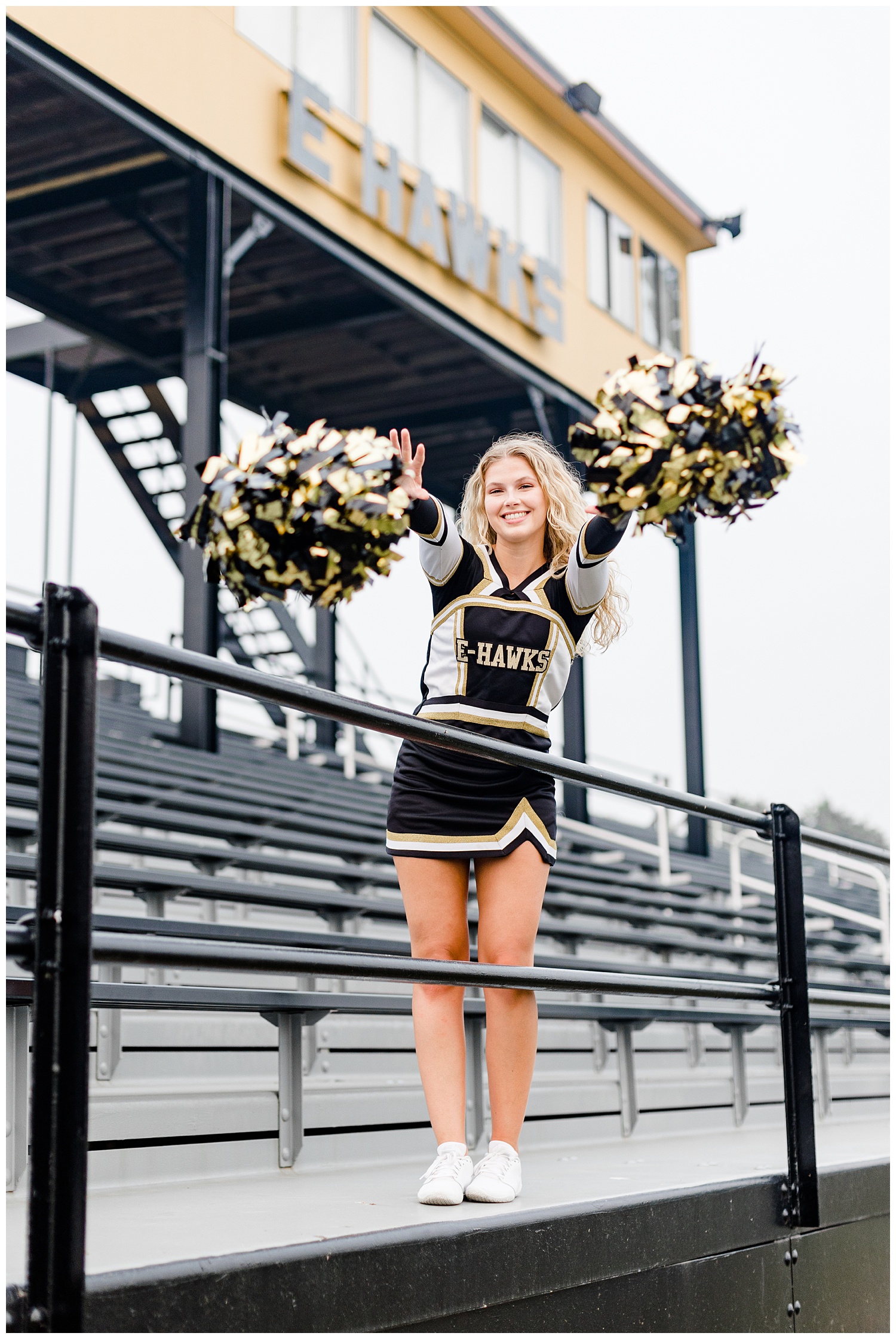 Senior Rachel from Emmetsburg High throws her cheerleading pows forward as she stands on the bleachers in the football field | CB Studio
