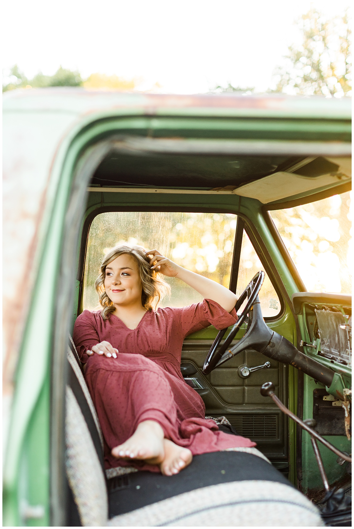 Cloey, wearing a vintage red dress, sits in an old, rusty green truck at golden hour | CB Studio
