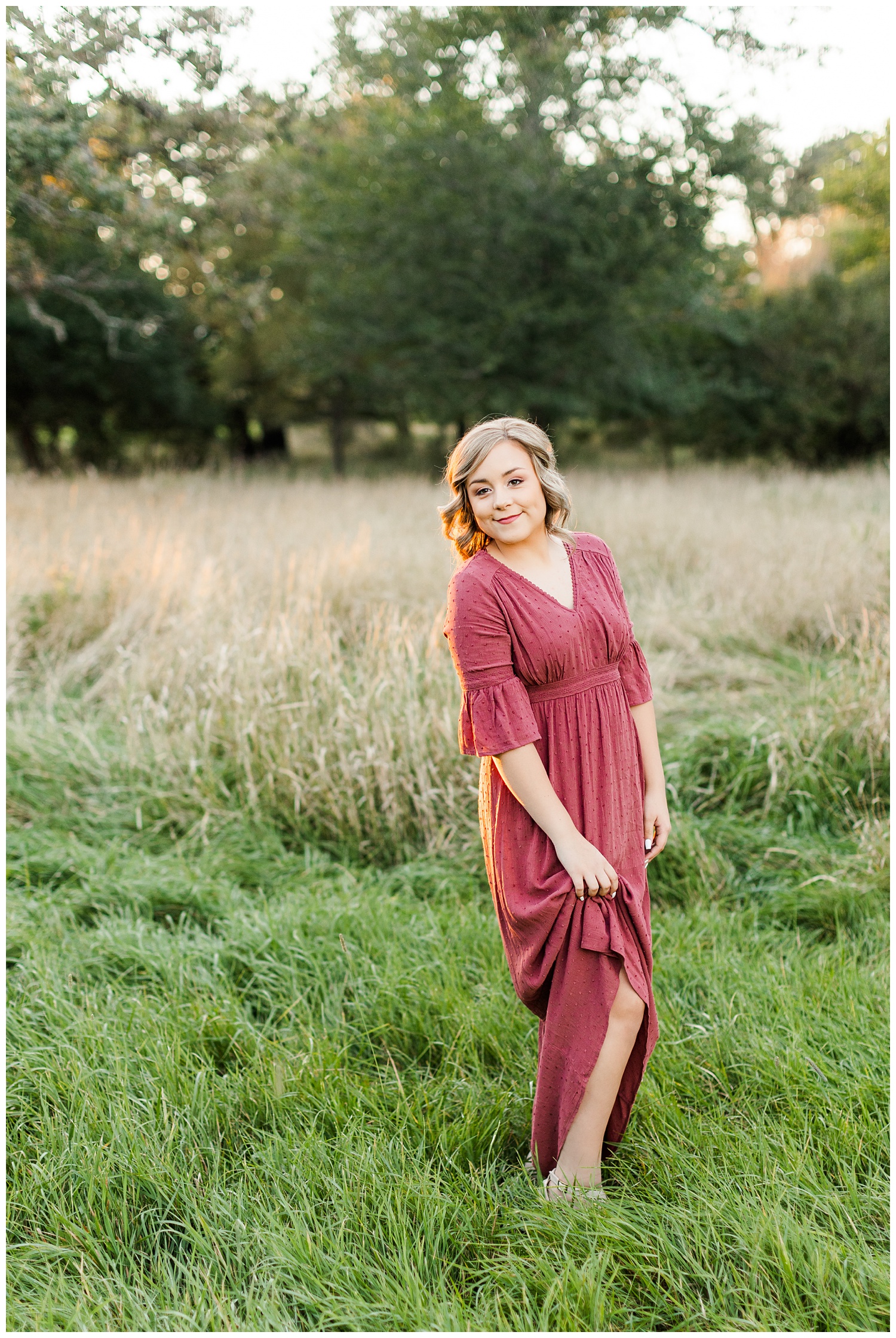 Cloey, wearing a vintage red dress, stands in a grassy pasture at golden hour | CB Studio