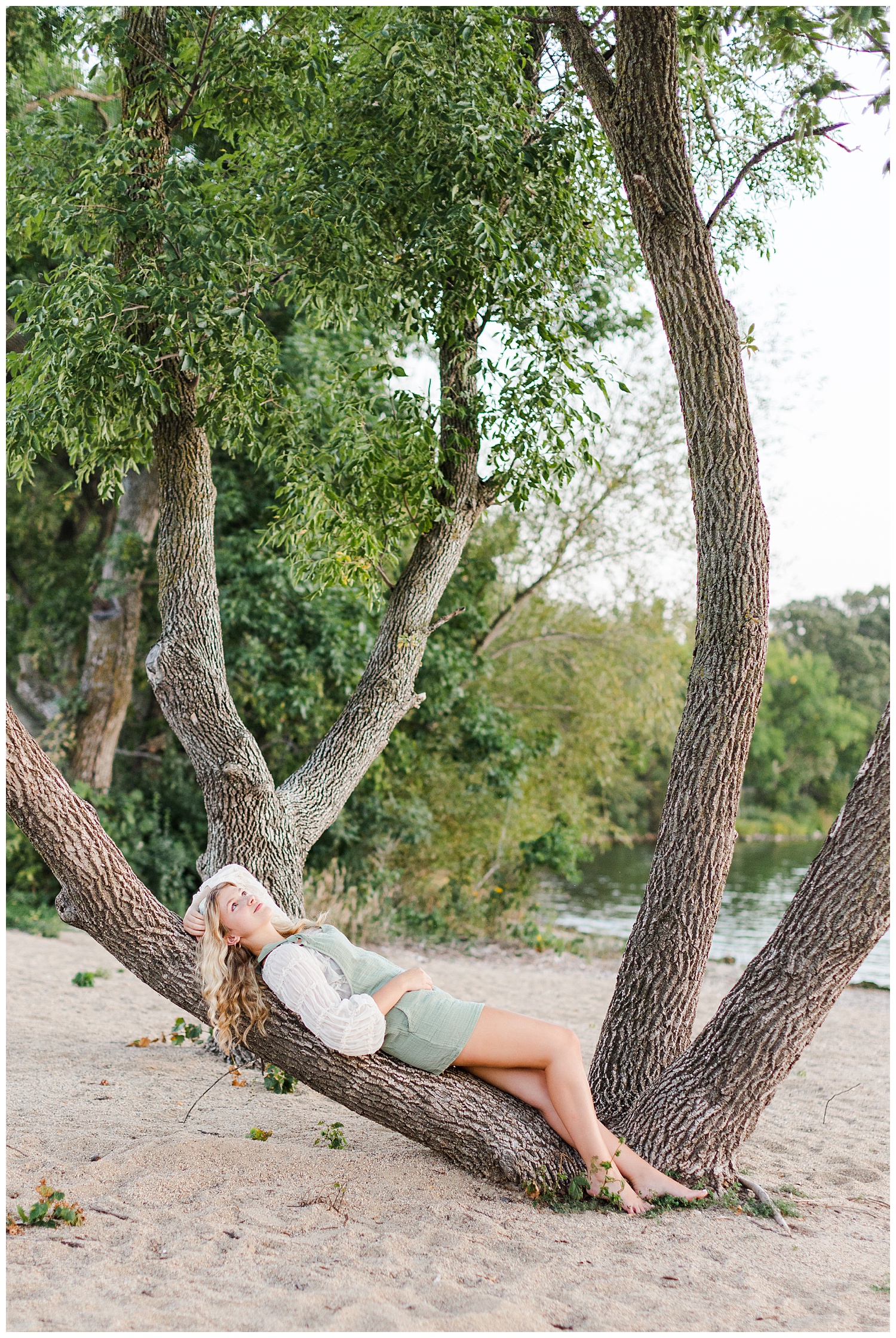 Rachel lays on a low tree branch at the beach at Lost Island Nature Center | CB Studio