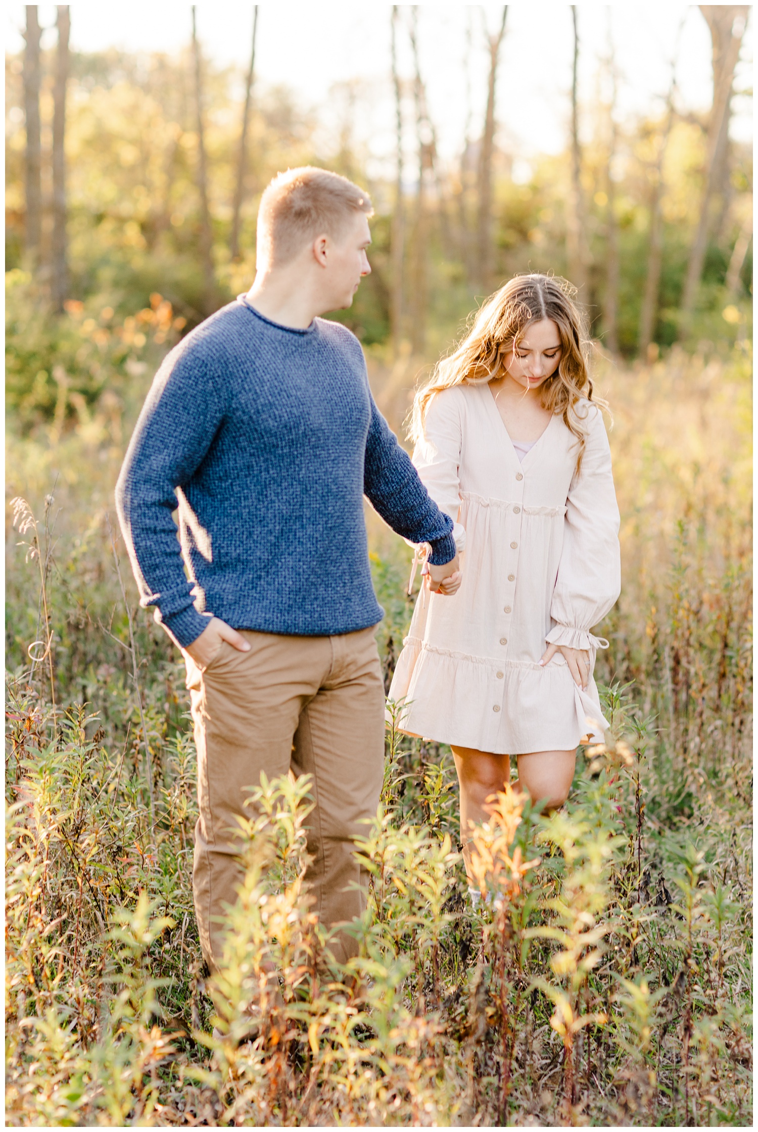 Ashlyn and Thad walk across a grassy pasture holding hands | CB Studio