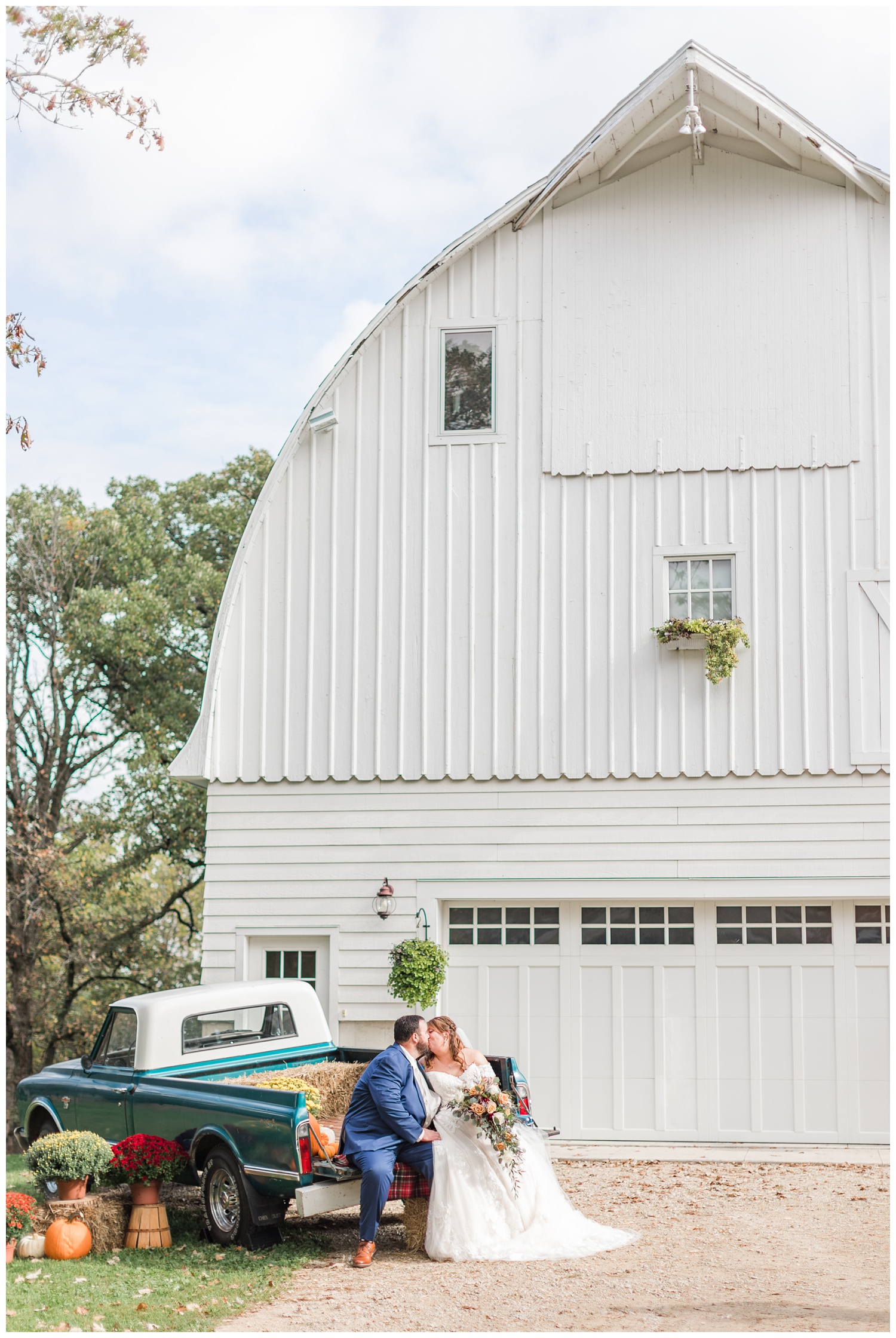 Bride and groom kiss in the back of an old Chevy truck in front of the white barn at Diamond Oak Events | CB Studio