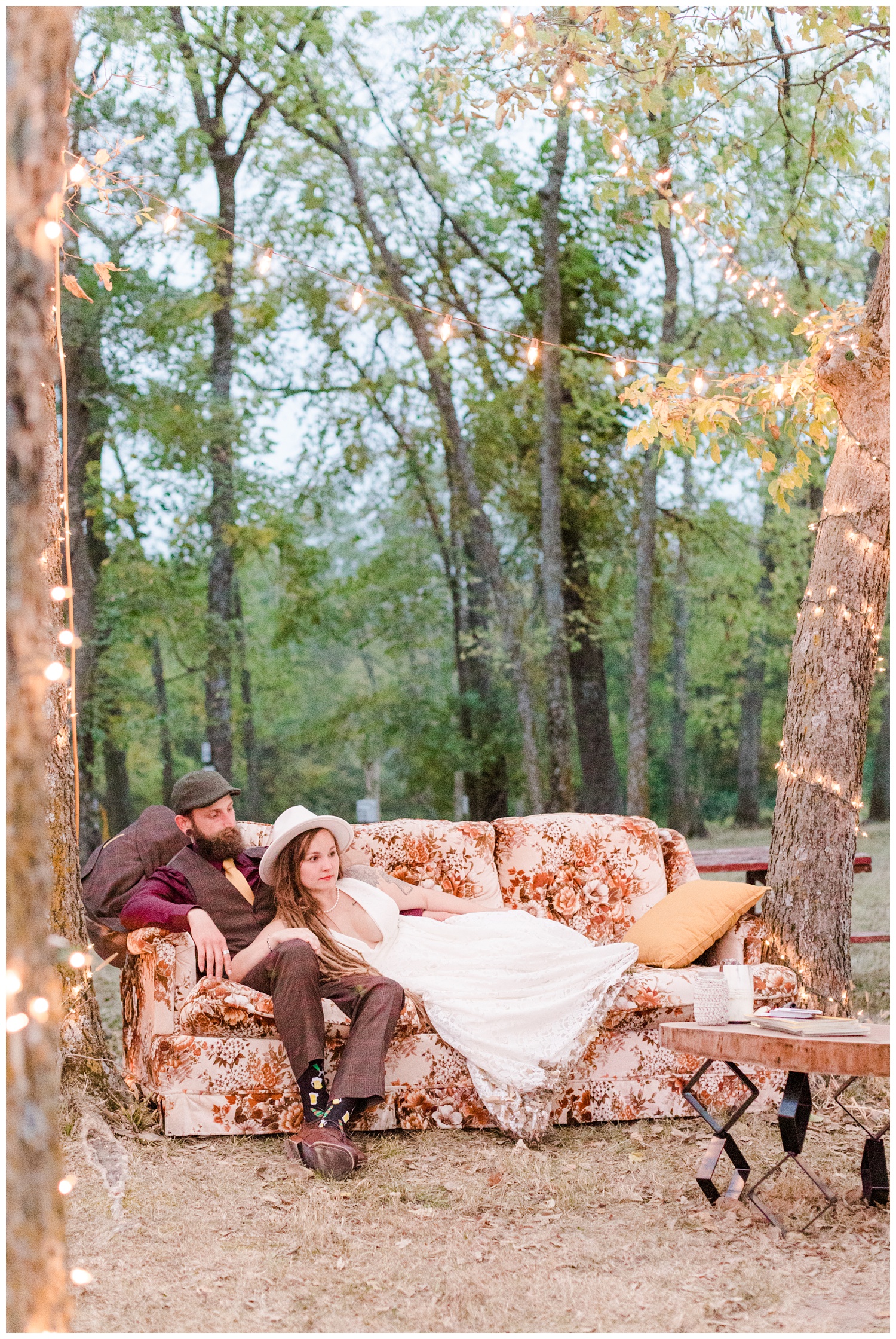 Authentic Boho Hippie bride and groom lay on a vintage couch in the woods | CB Studio