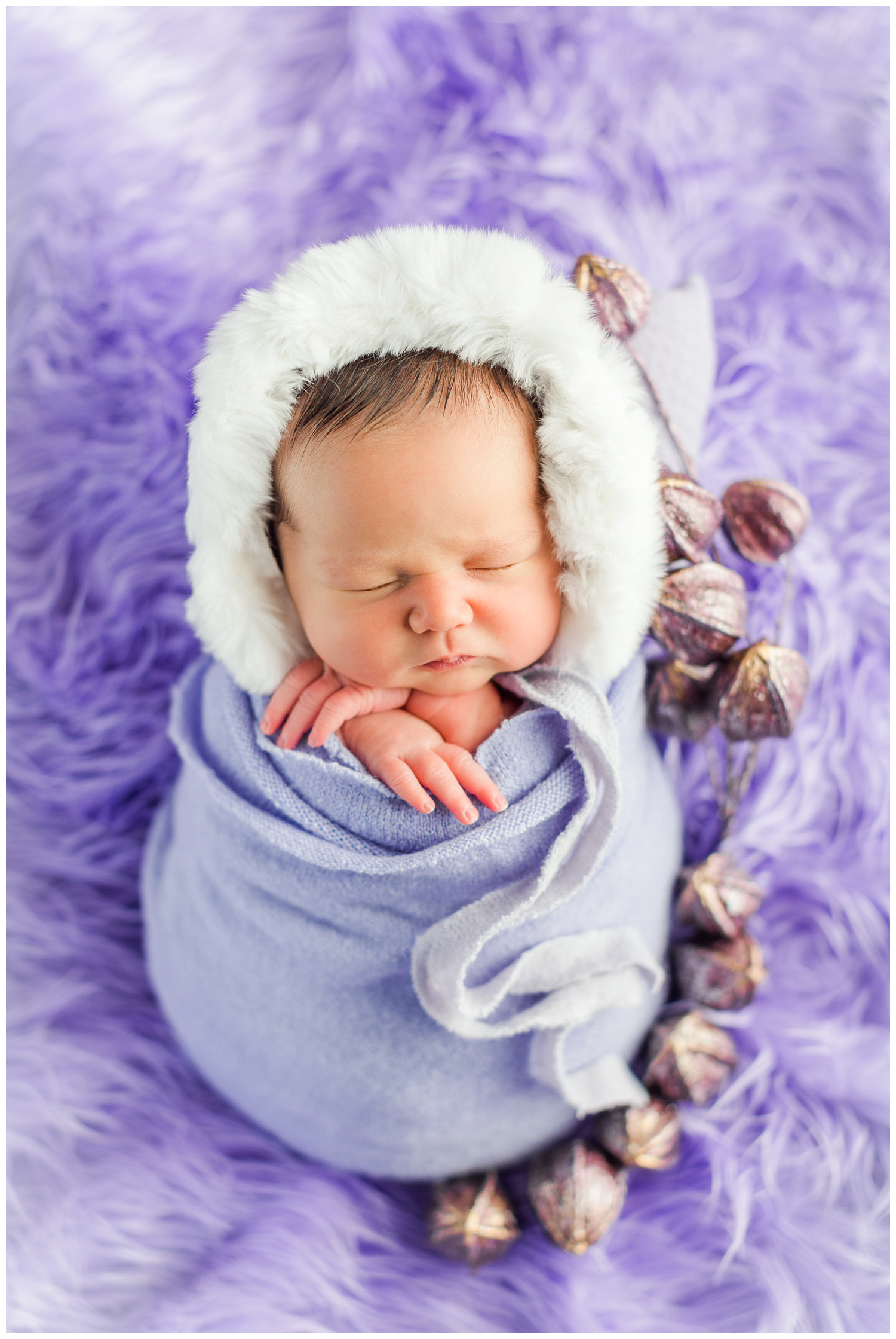 Baby Letti wrapped in lavender wearing a fluffy eskimo bonnet surrounded my purple floral | CB Studio