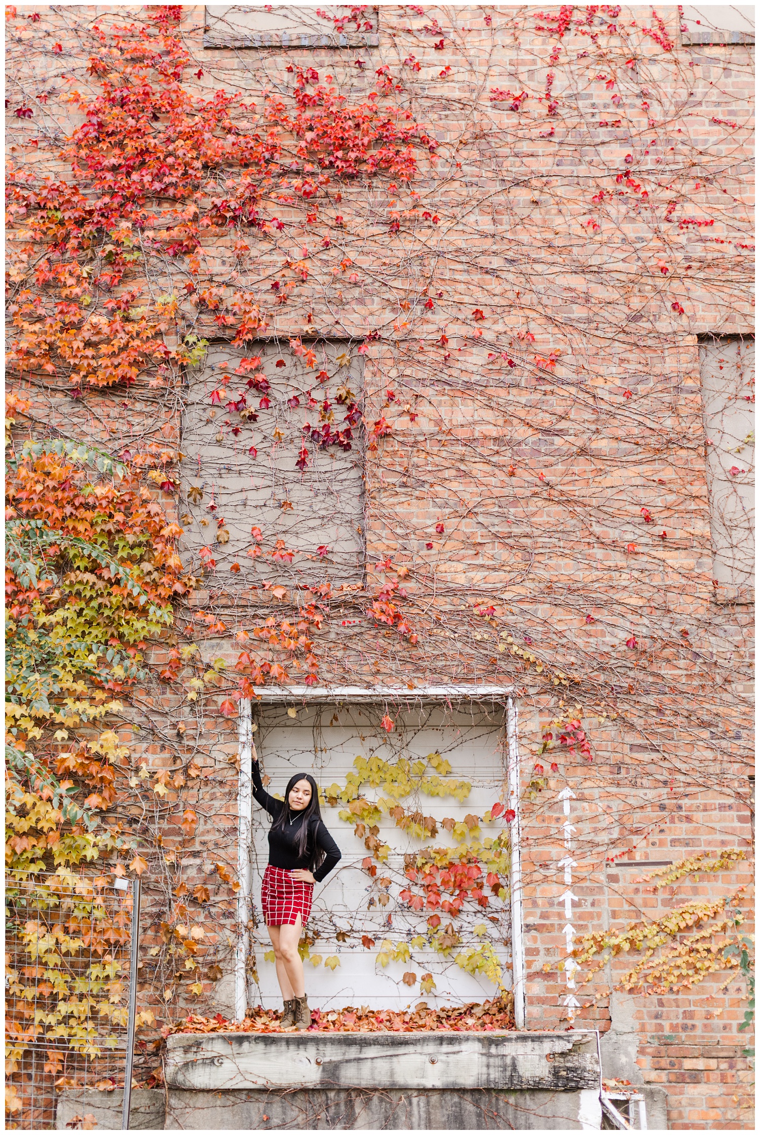 Doris leans against an old warehouse building covered in beautiful fall colored leaves in downtown Fort Dodge | CB Studio