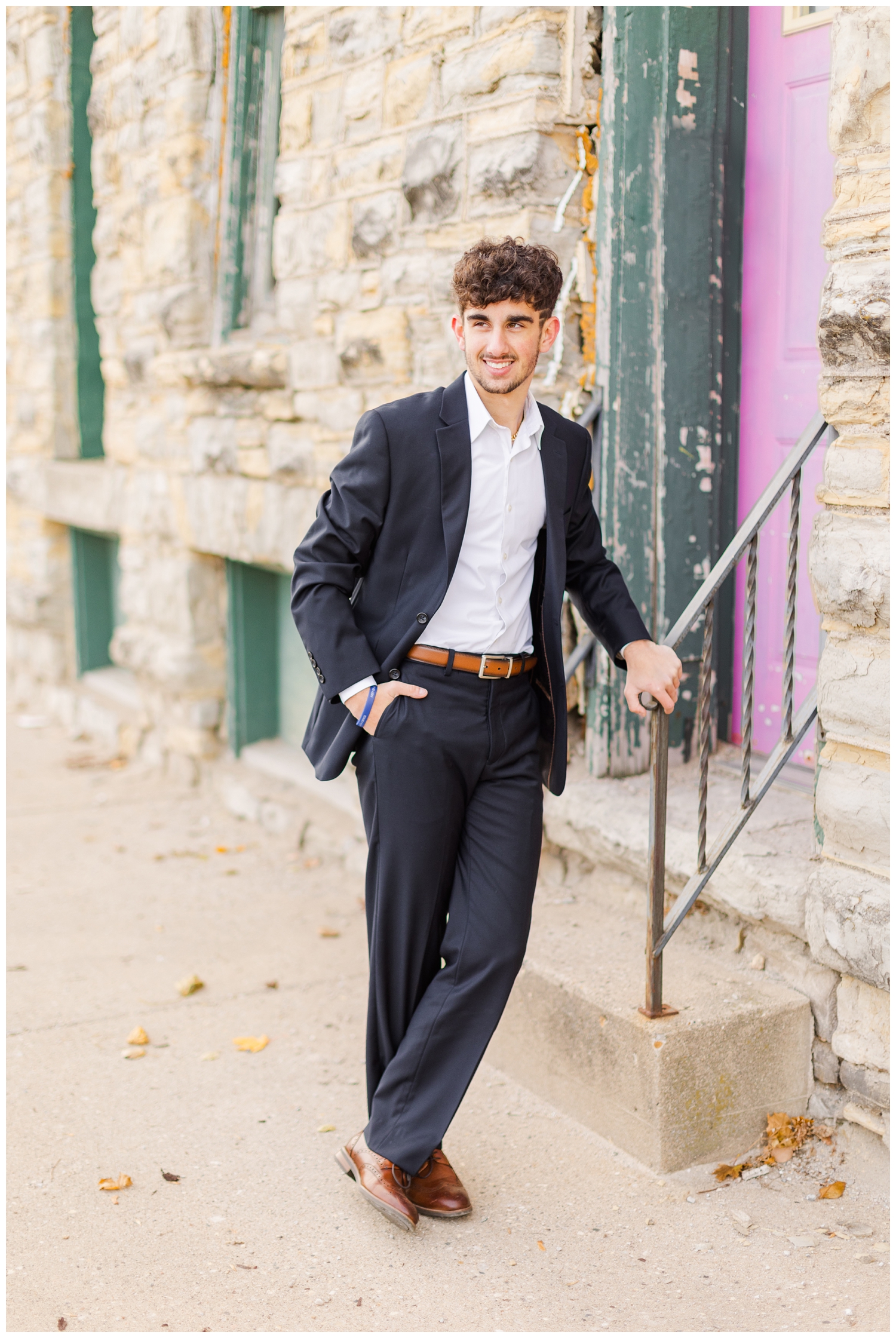 Sam wearing a black suit leans over a stair rail in downtown Humboldt, IA | CB Studio