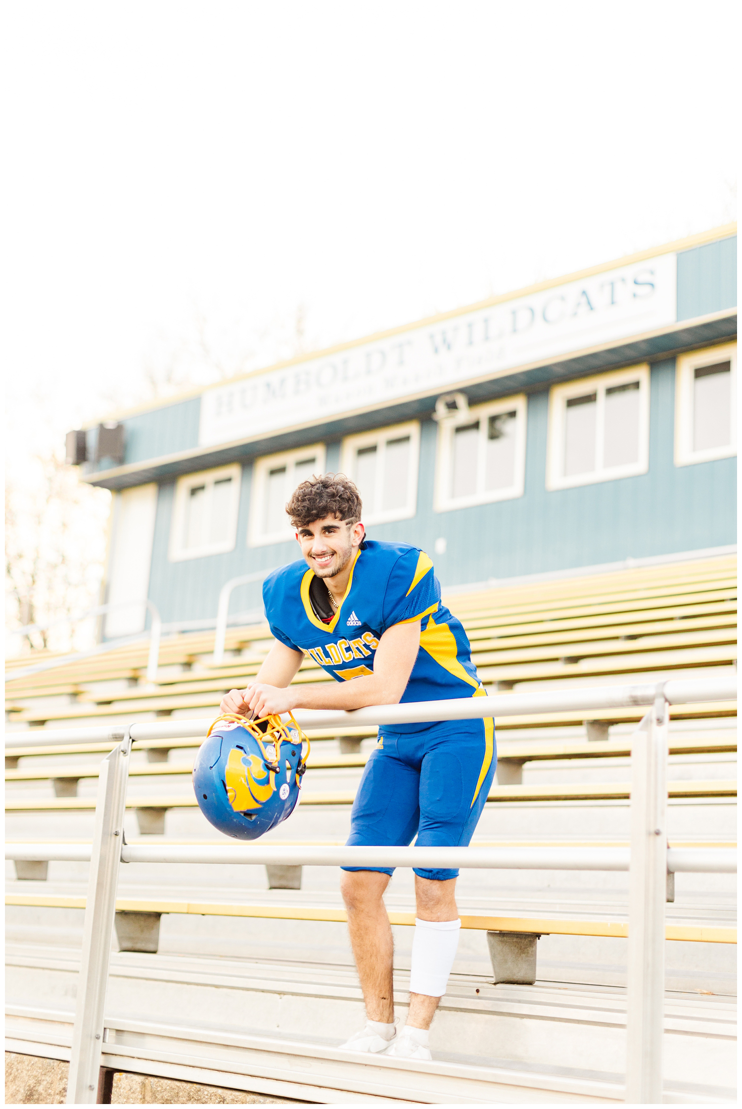 Sam, a senior football player at Humboldt HS, leans over the bleach railing on the foot ball field | CB Studio